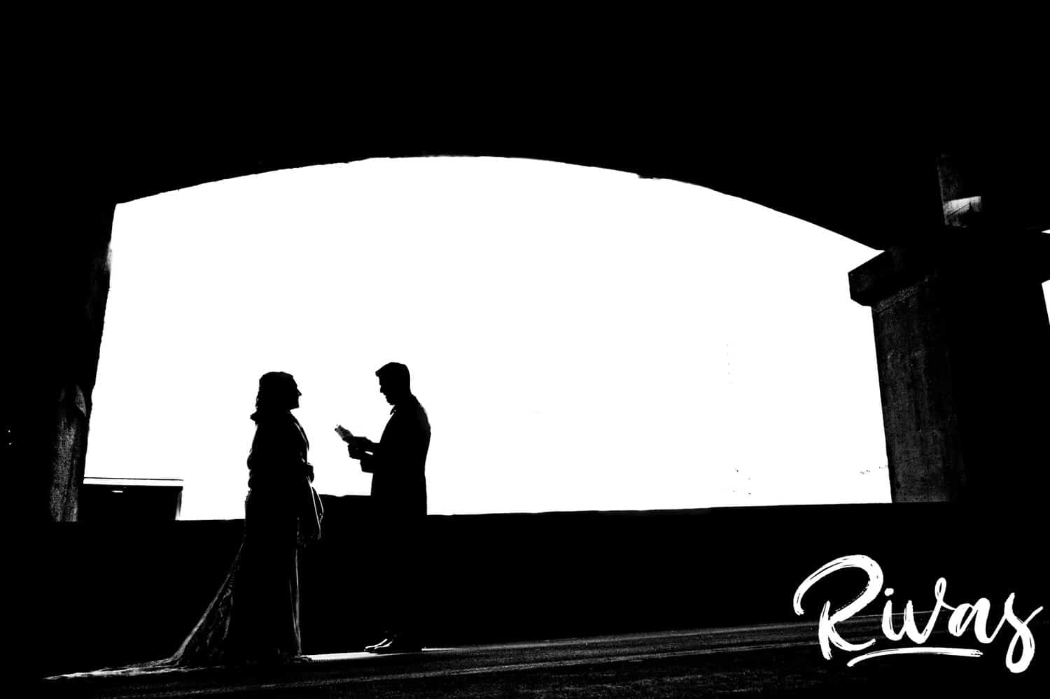 A bold black and white silhouette of a groom reading his vows to his bride on the 12th street Viaduct in Kansas city on the afternoon of their fall wedding reception at The Foundation Event Space. 