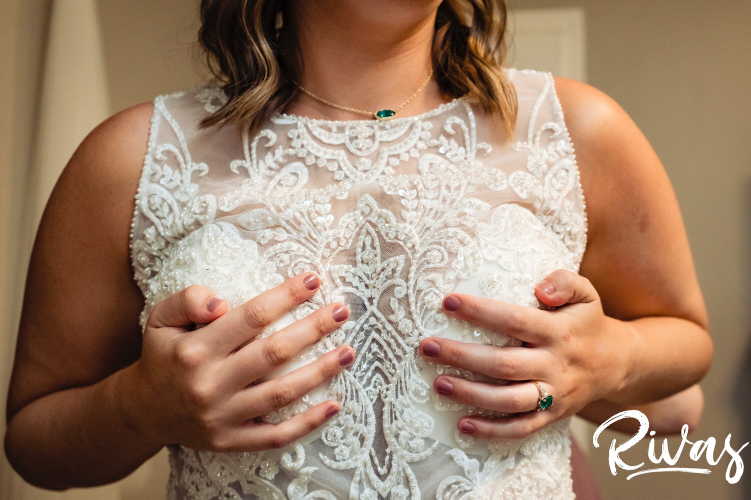 A candid picture of a bride holding her boobs and dress up as her sister buttons the back on the day of her wedding reception at the Museum at Prairiefire. 