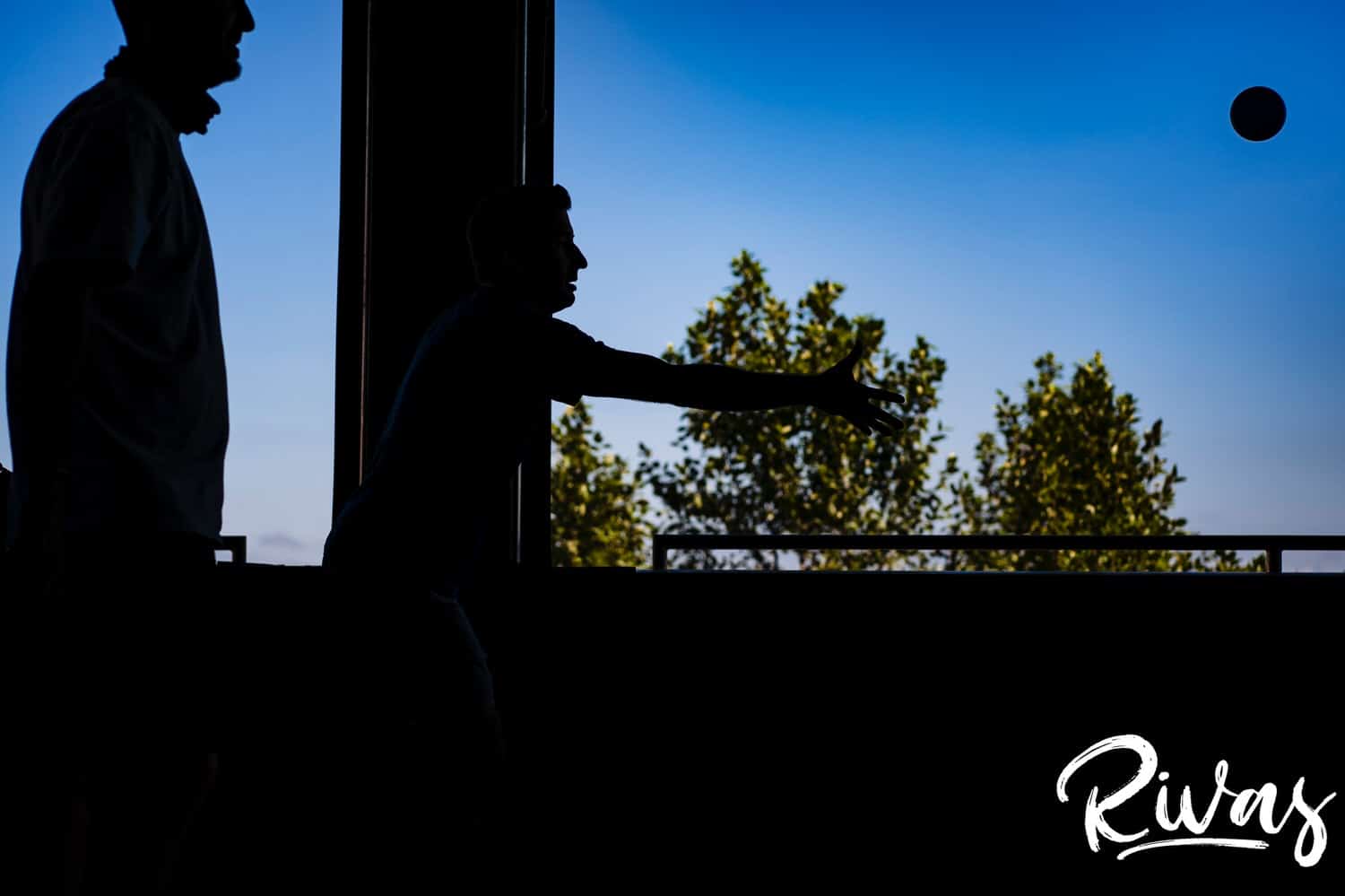 A colorful silhouette of a man throwing a bocce ball on the morning of a Kansas City summer wedding. 
