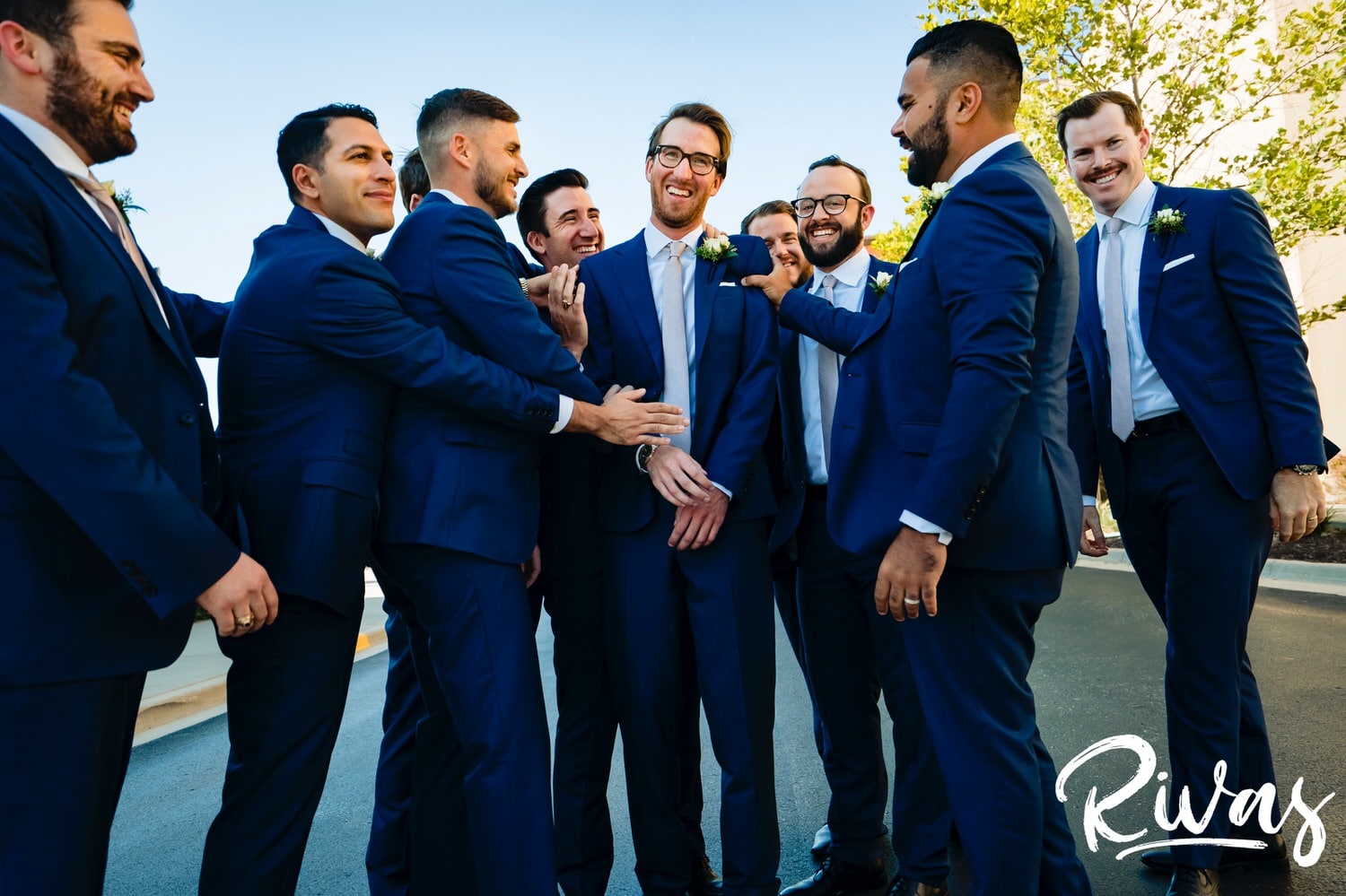 A colorful, candid picture of a groom and his groomsmen walking down the street laughing on the afternoon of a wedding reception at The Museum at Prairiefire in Kansas City. 