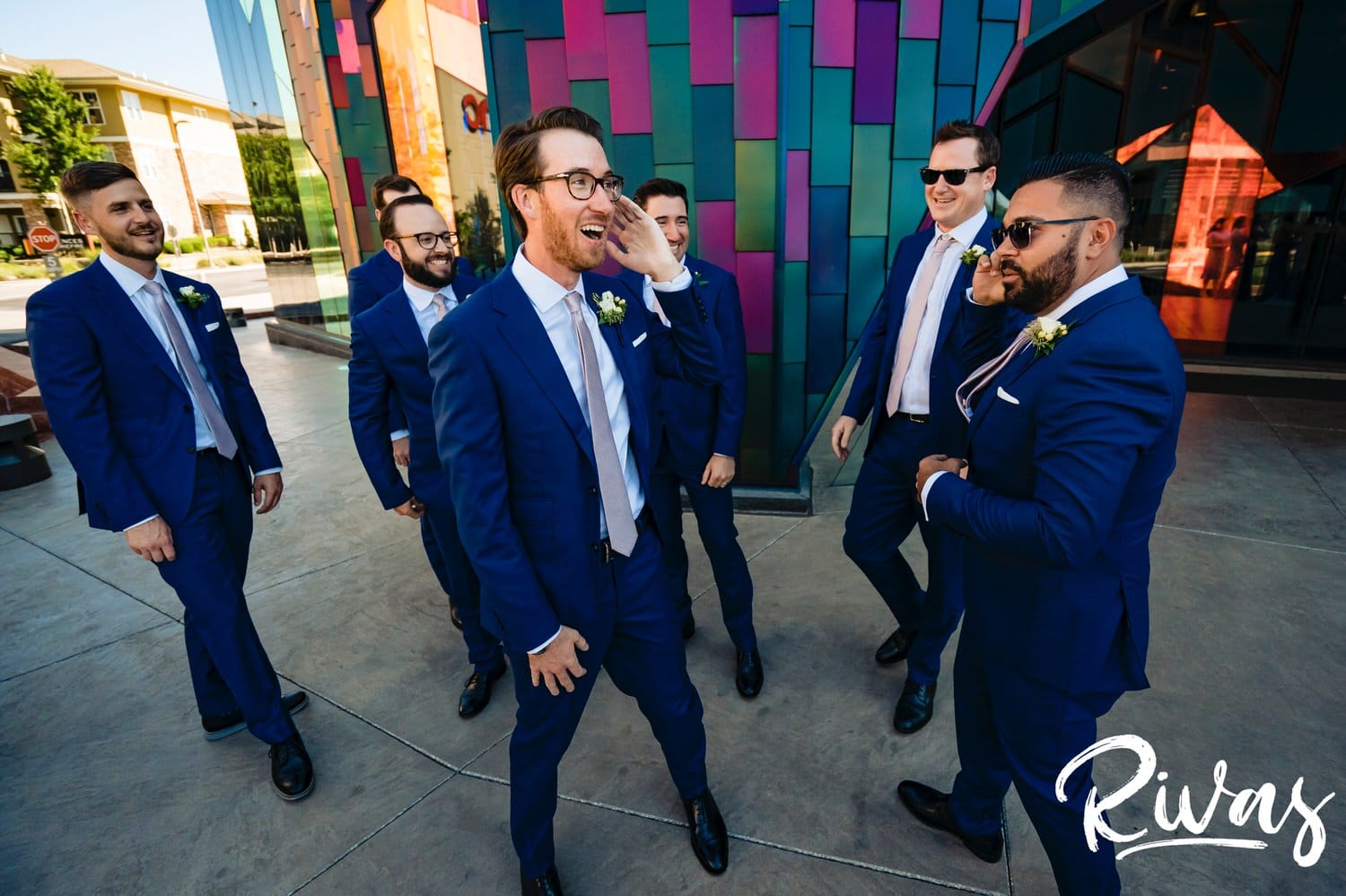 A colorful, candid picture of a groom and his groomsmen walking down the street laughing on the afternoon of a wedding reception at The Museum at Prairiefire in Kansas City. 