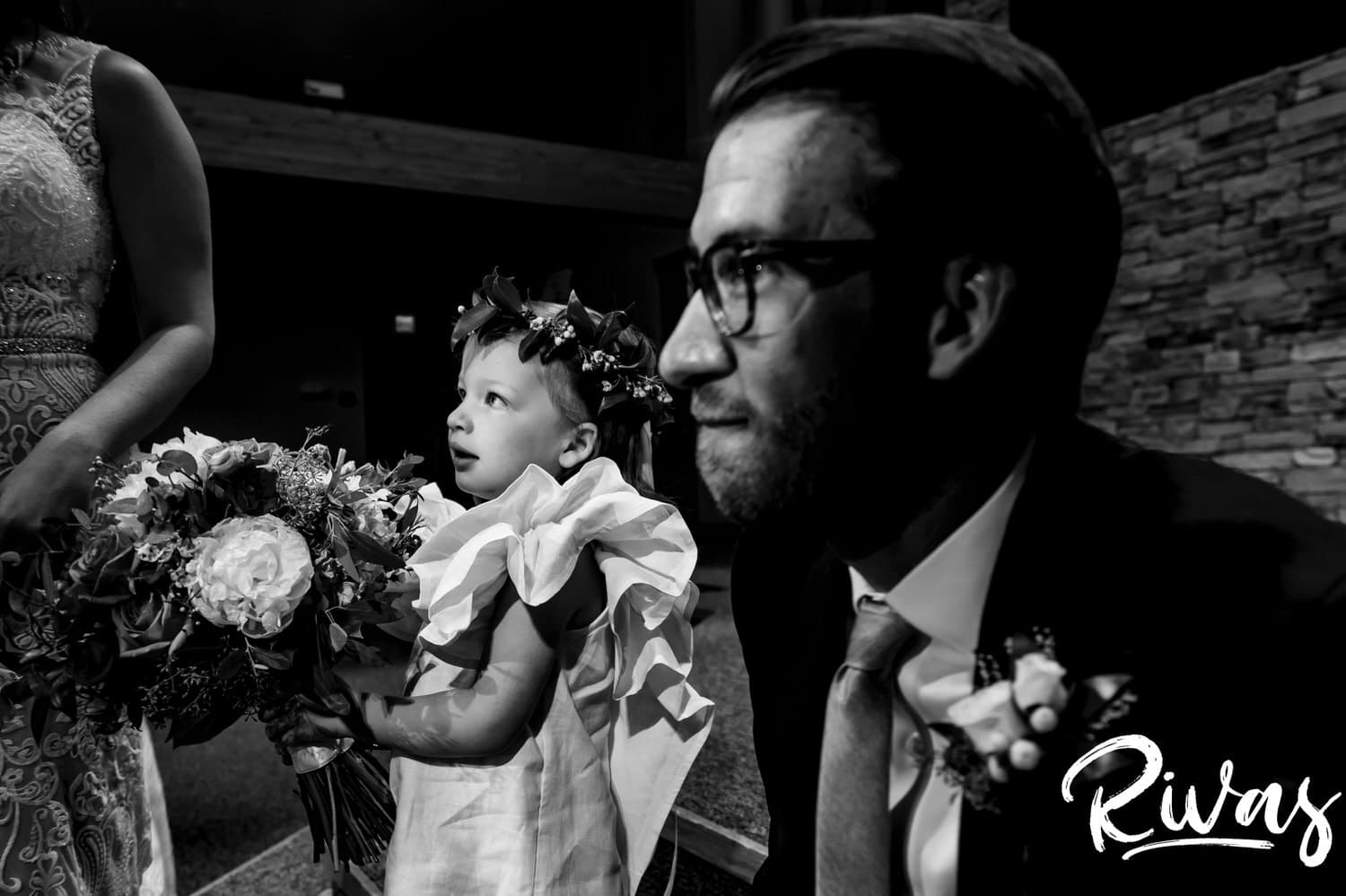 A candid, up-close picture of a groom smiling and helping his niece hold a large bouquet on the afternoon of his wedding in Kansas City. 