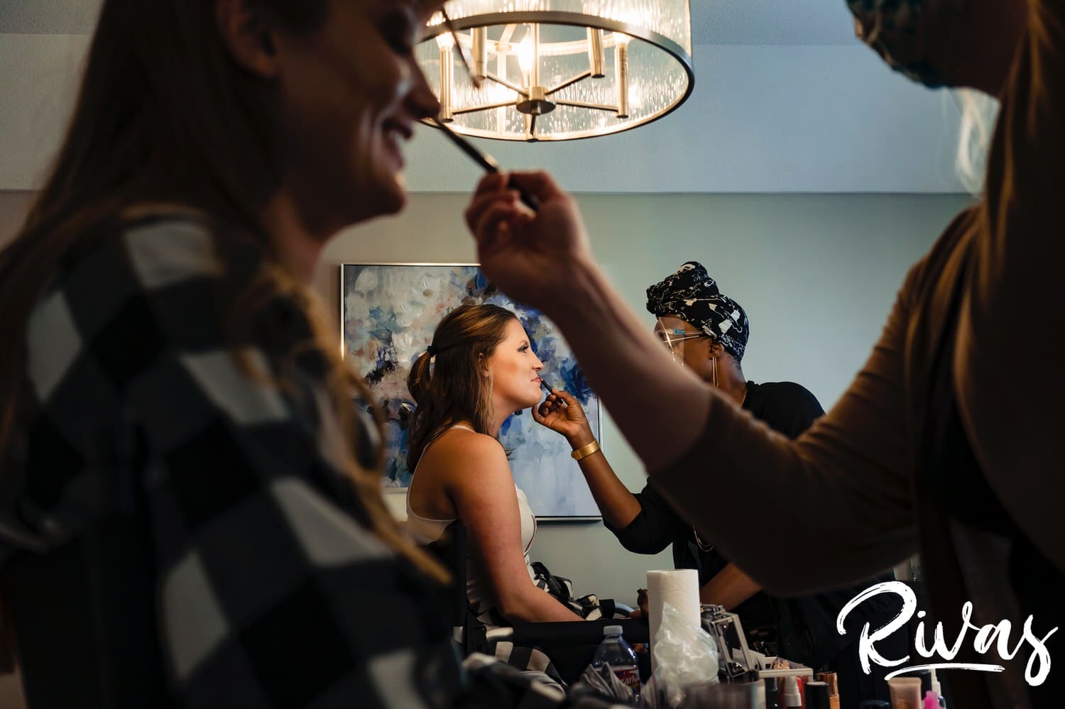 A candid picture of a bride and her bridesmaid getting their makeup done on the morning of their Kansas City Wedding. 
