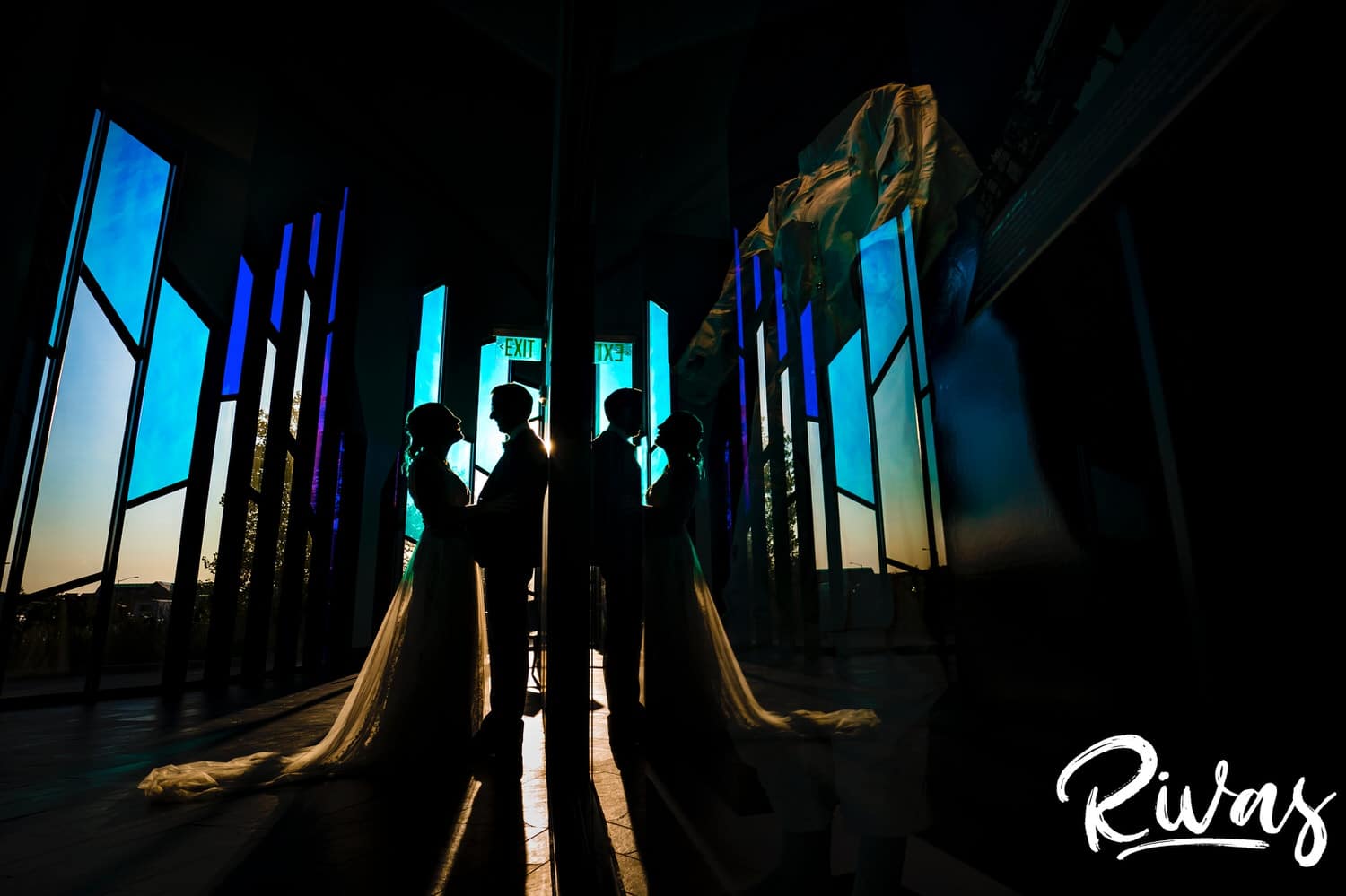 A colorful silhouette of a bride and groom holding hands, laughing together on the evening of their wedding reception at The Museum at Prairiefire. 