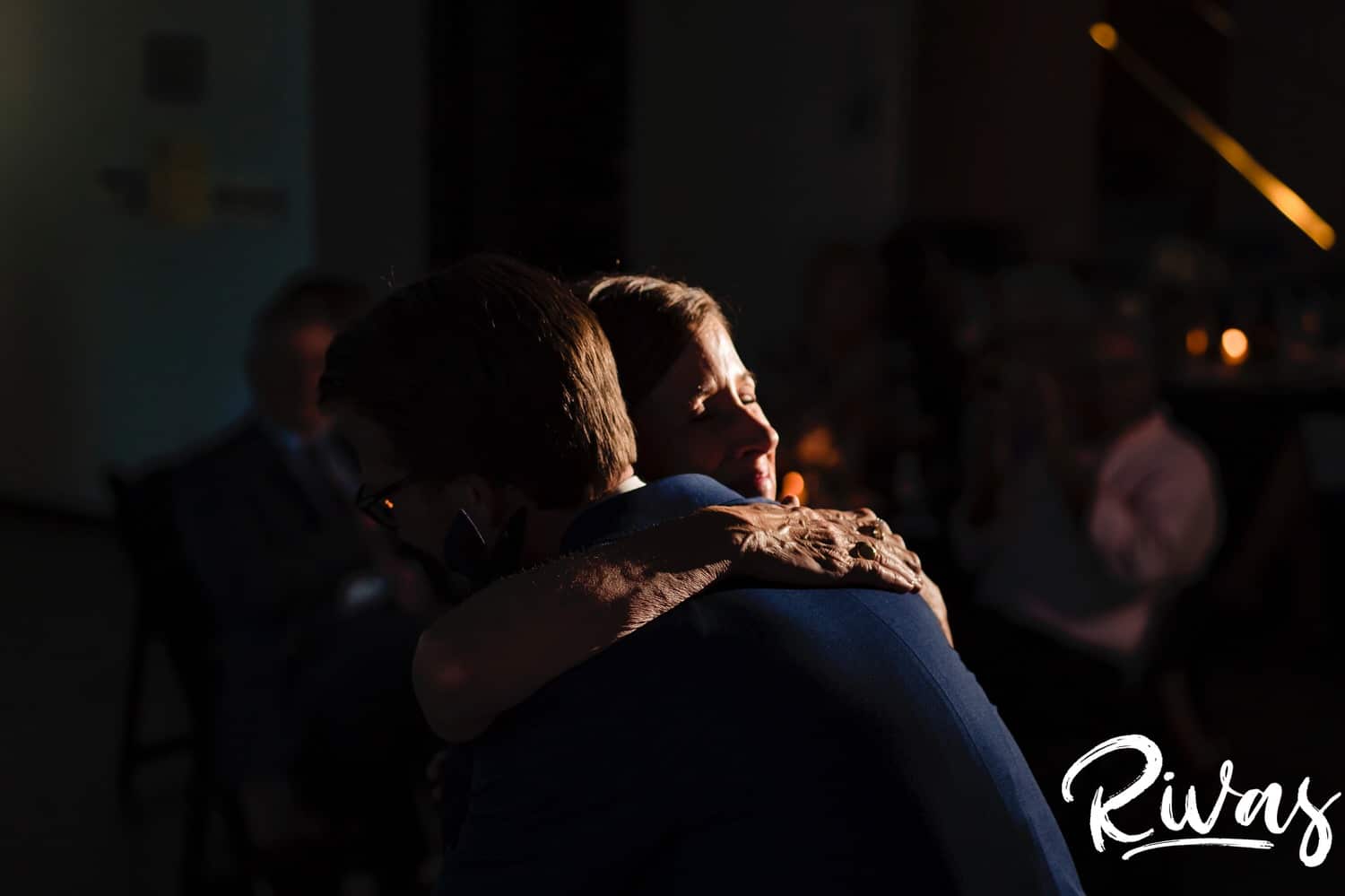 A candid picture of a groom's mom hugging him tightly at the end of their dance during a Museum at Prairiefire wedding reception. 