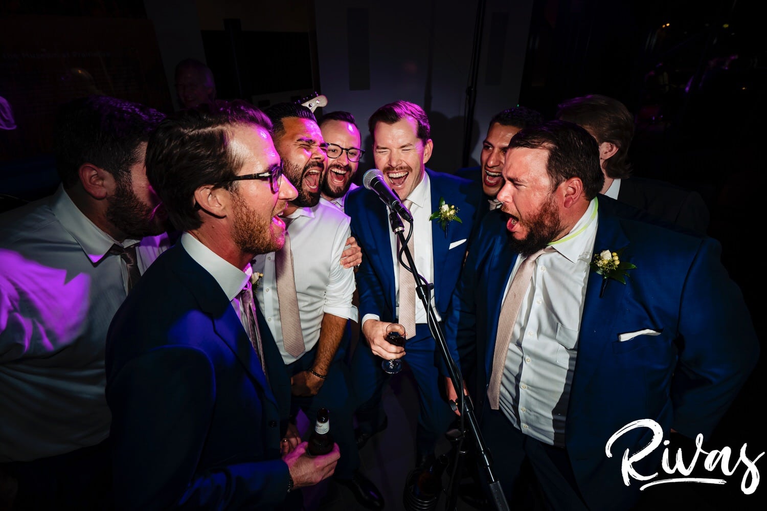 A candid picture of a groom, surrounded by his groomsmen singing outloud and dancing during his Museum at Prairiefire wedding reception. 