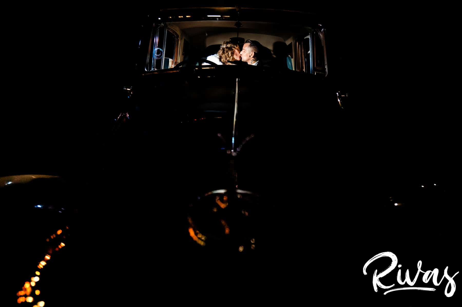 A dark and dramatic portrait taken from the very front of a car of a bride and groom sitting in the back of an old Bentley on the night of their Longview Mansion Wedding day. 