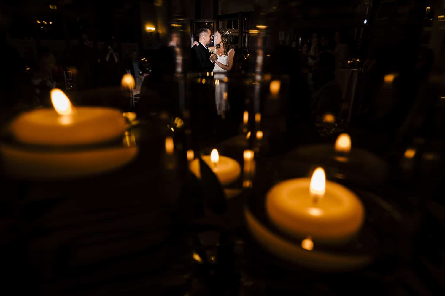A dramatic, colorful picture taken over a candlescape of a bride and groom sharing their first dance during their wedding reception at Longview Mansion. 