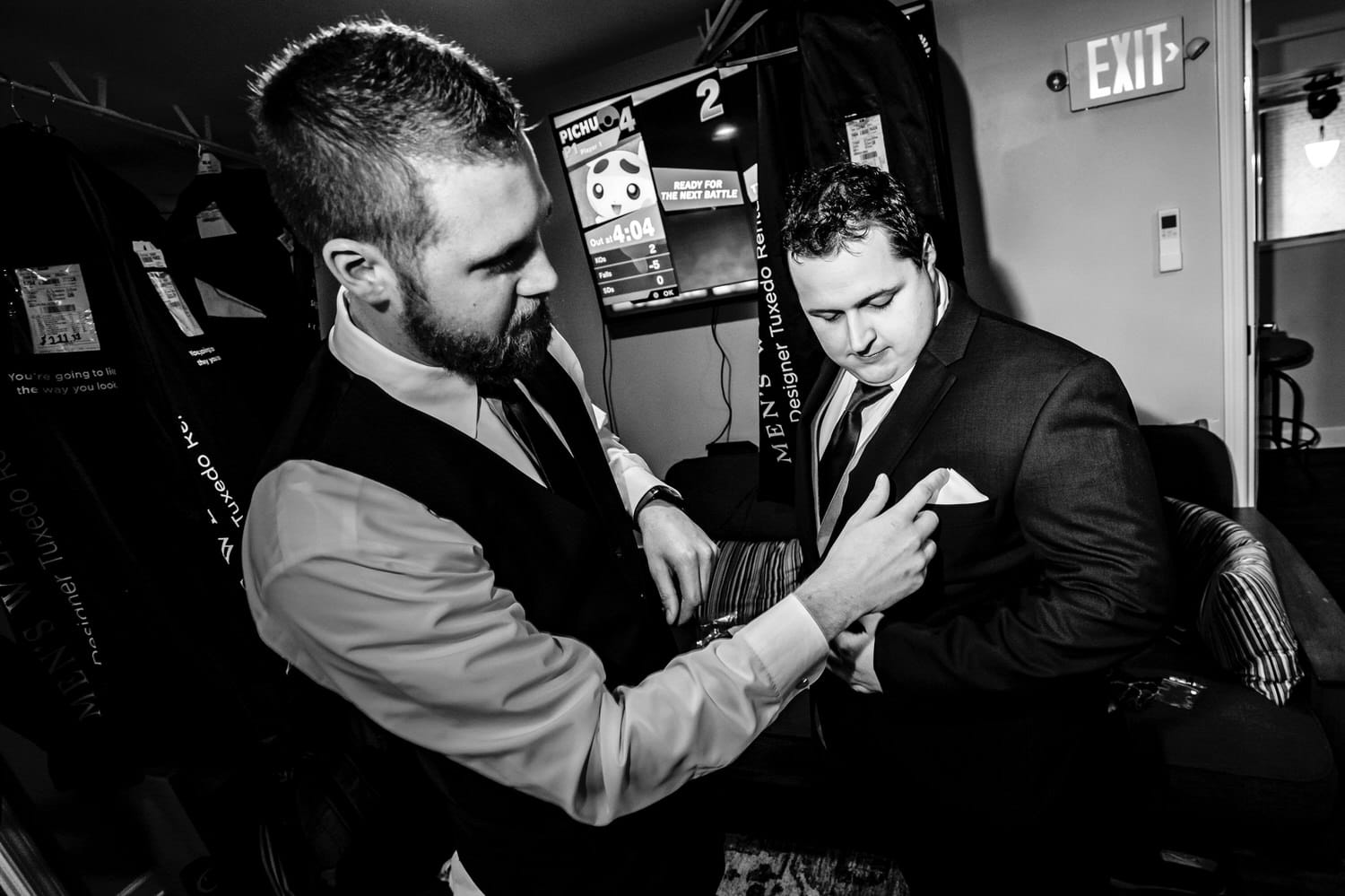 A candid black and white picture of a groom's best man adjusting the pocket square of the groom's suit on his winter wedding day in Kansas City at The Station. 
