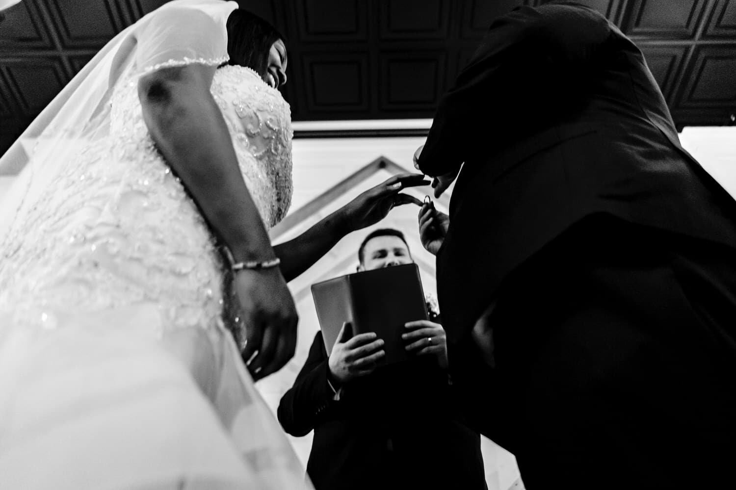 A candid black and white picture taken from the ground looking up as a bride and groom exchange their vows during a winter wedding ceremony in Kansas City at The Station. 