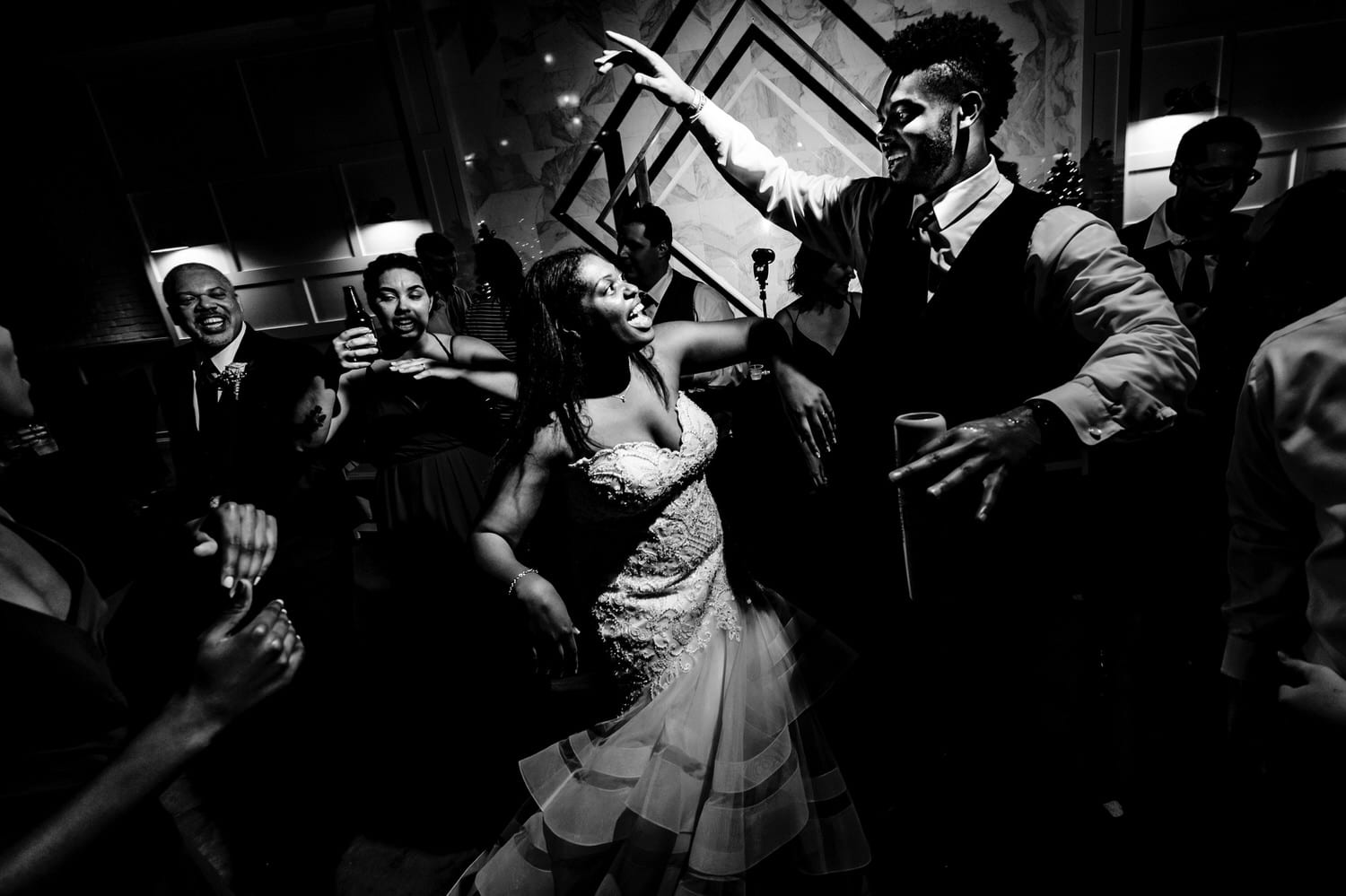 A candid black and white picture of a bride dancing and singing with her brother on the dance floor during her winter wedding reception at The Station in Kansas City. 