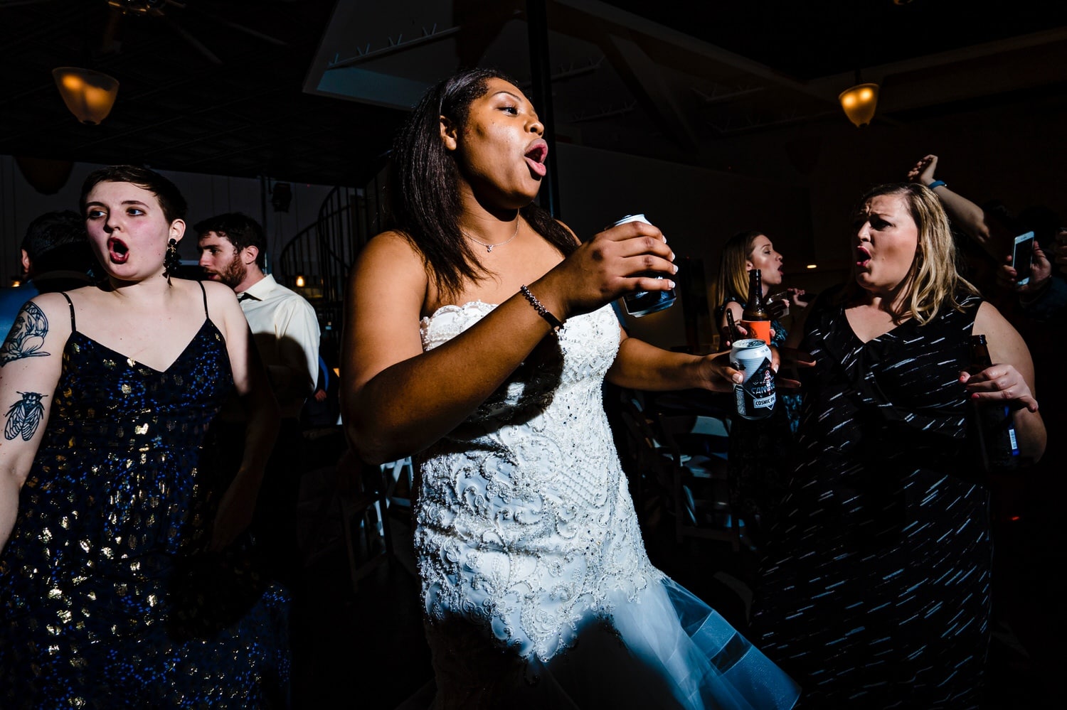 A colorful, candid picture of a bride and groom in the middle of the dance floor, surrounded by friends and family during their winter wedding reception at The Station in Kansas City. 