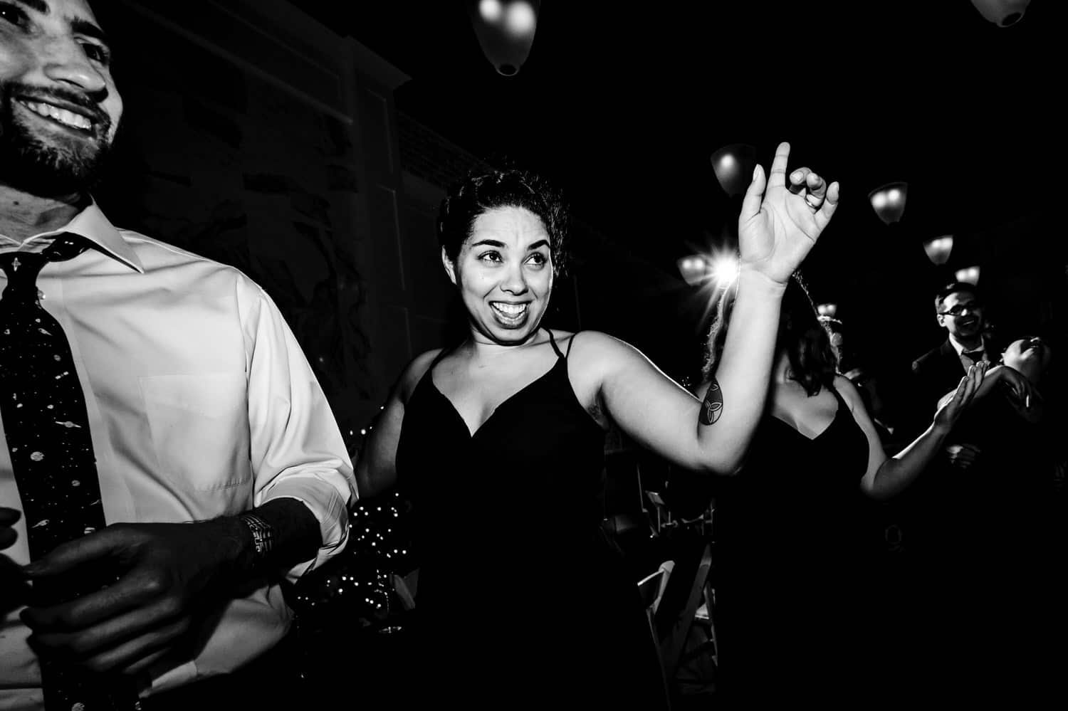 A candid black and white picture of a bridesmaid dancing excitedly in the middle of the dance floor during a winter wedding reception at The Station in Kansas City. 