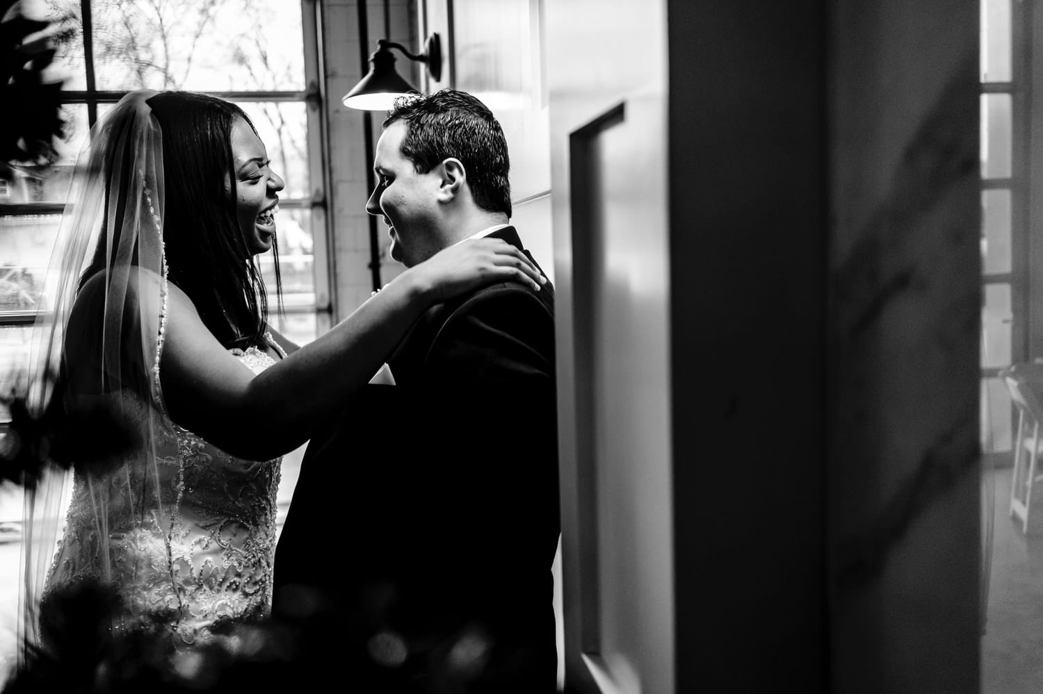 A black and white portrait of a bride leaning in to give her groom a kiss on the afternoon of their rainy winter wedding day at The Station in Kansas City. 