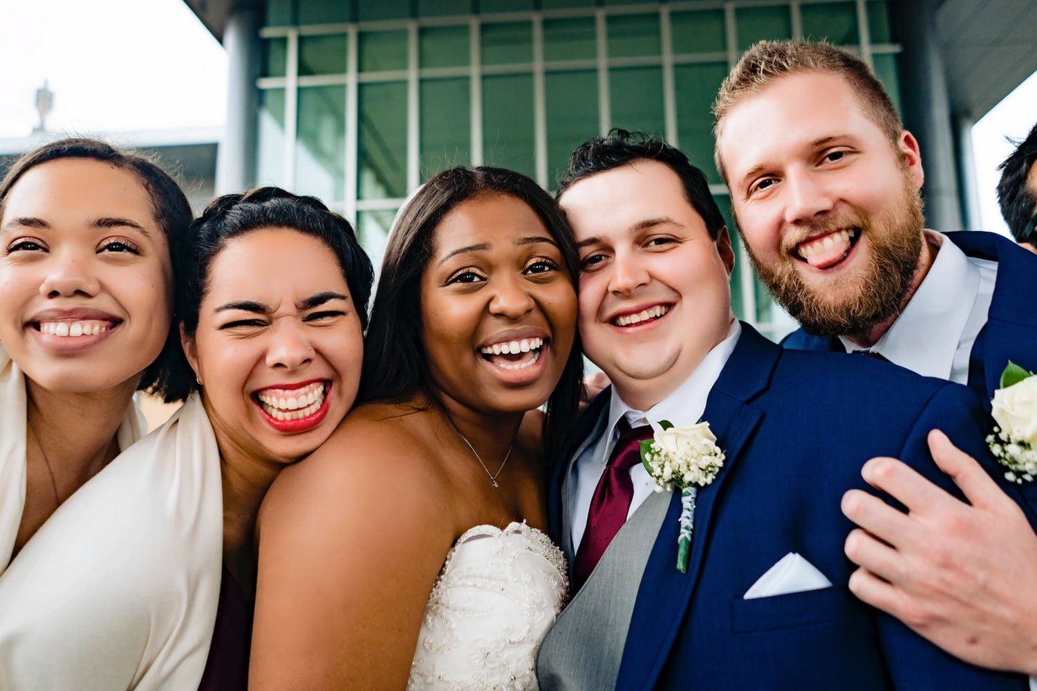 A close-up, candid picture of a bride and groom with their wedding party laughing and smiling for the camera on a rainy winter wedding in downtown Kansas City. 