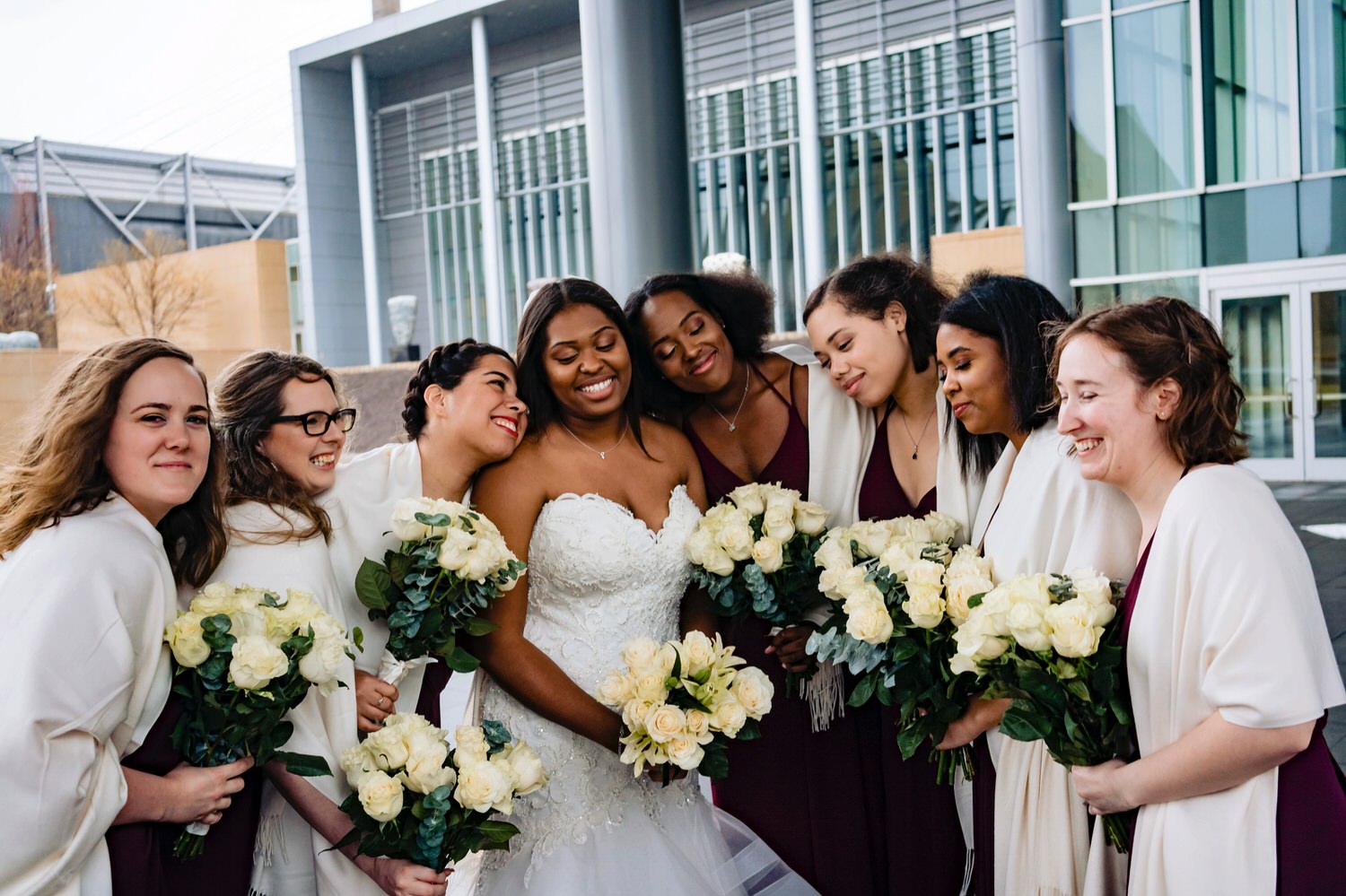 A close-up, candid picture of a bride and her bridesmaids laughing and smiling for the camera on a rainy winter wedding in downtown Kansas City. 
