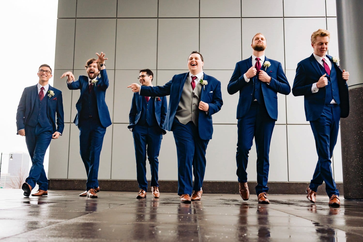 A close-up, candid picture of a groom and his groomsmen laughing and smiling for the camera on a rainy winter wedding in downtown Kansas City. 