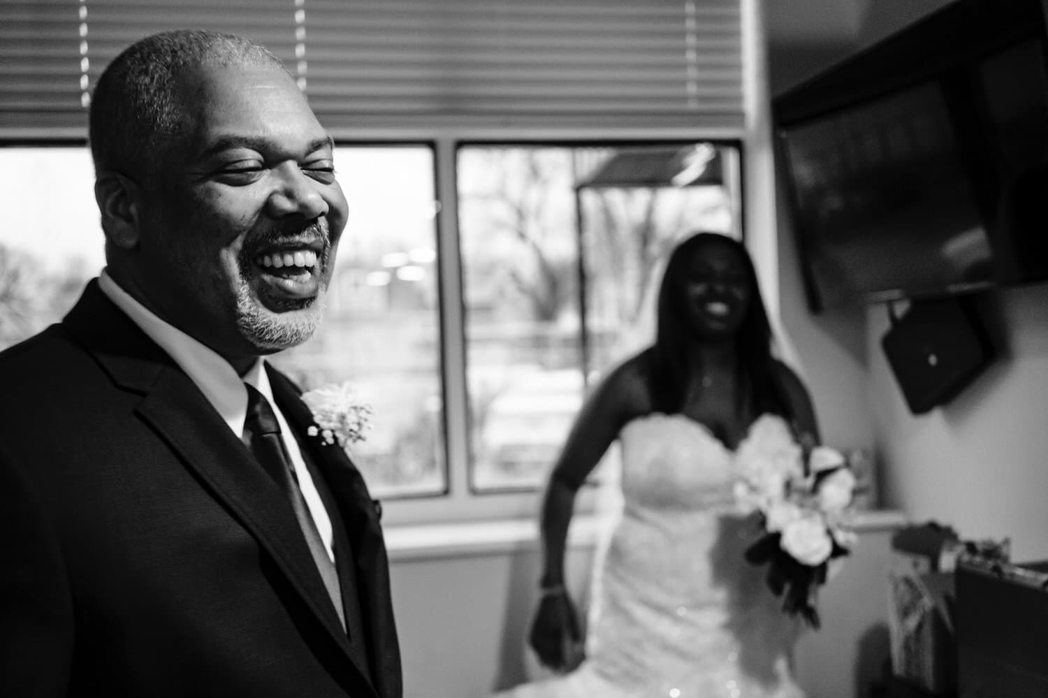 A candid black and white picture of a bride and her dad laughing together, moments before they walk down the aisle on a rainy winter wedding day at The Station in Kansas City. 