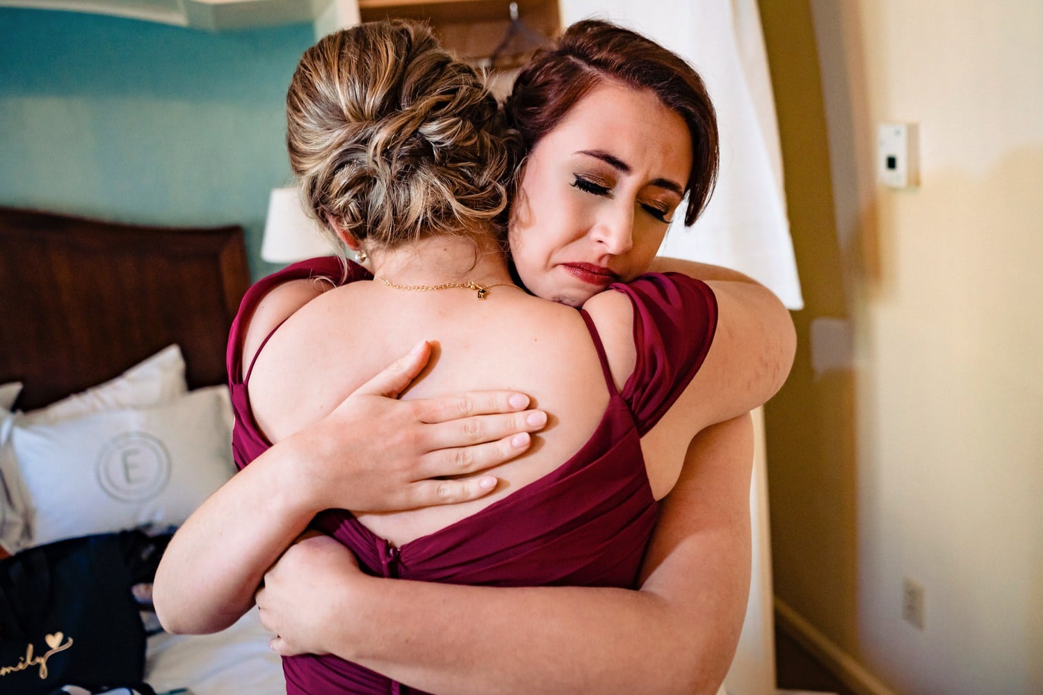 A colorful, candid picture of a bride emotionally hugging her sister on the afternoon of a sunny winter wedding at The Elms. 