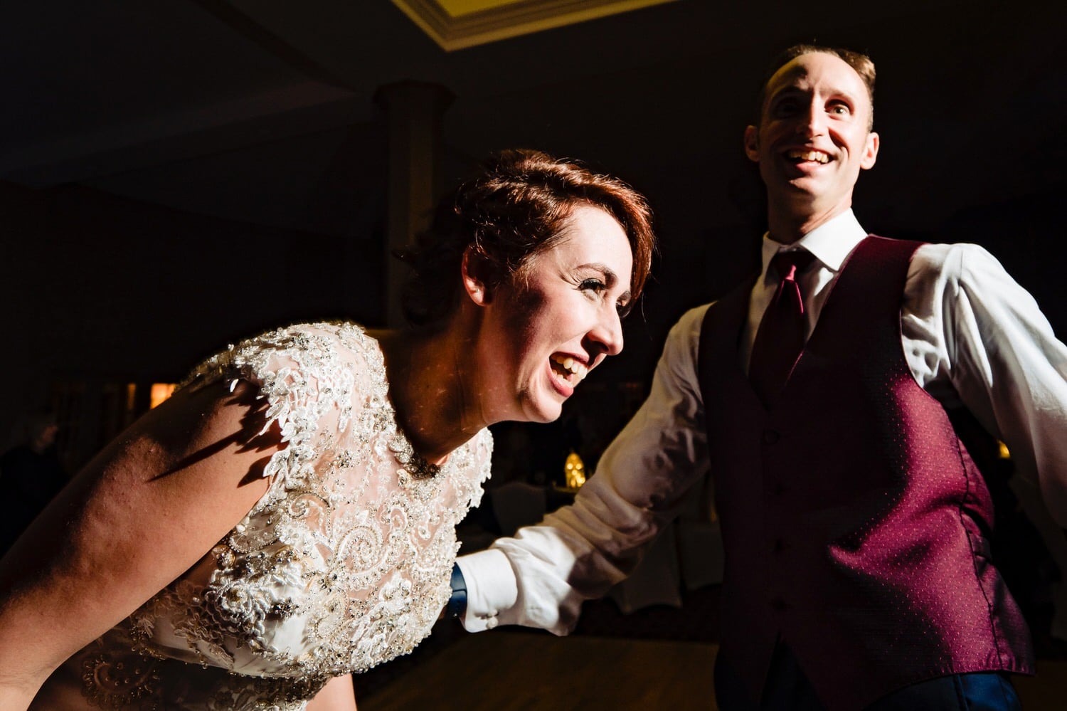 A close-up, candid picture of a bride and groom laughing hysterically during their wedding reception at The Elms. 