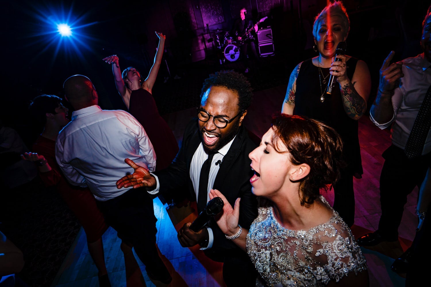 A close-up, candid picture of a bride singing into a microphone with a band member during her wedding reception at The Elms. 