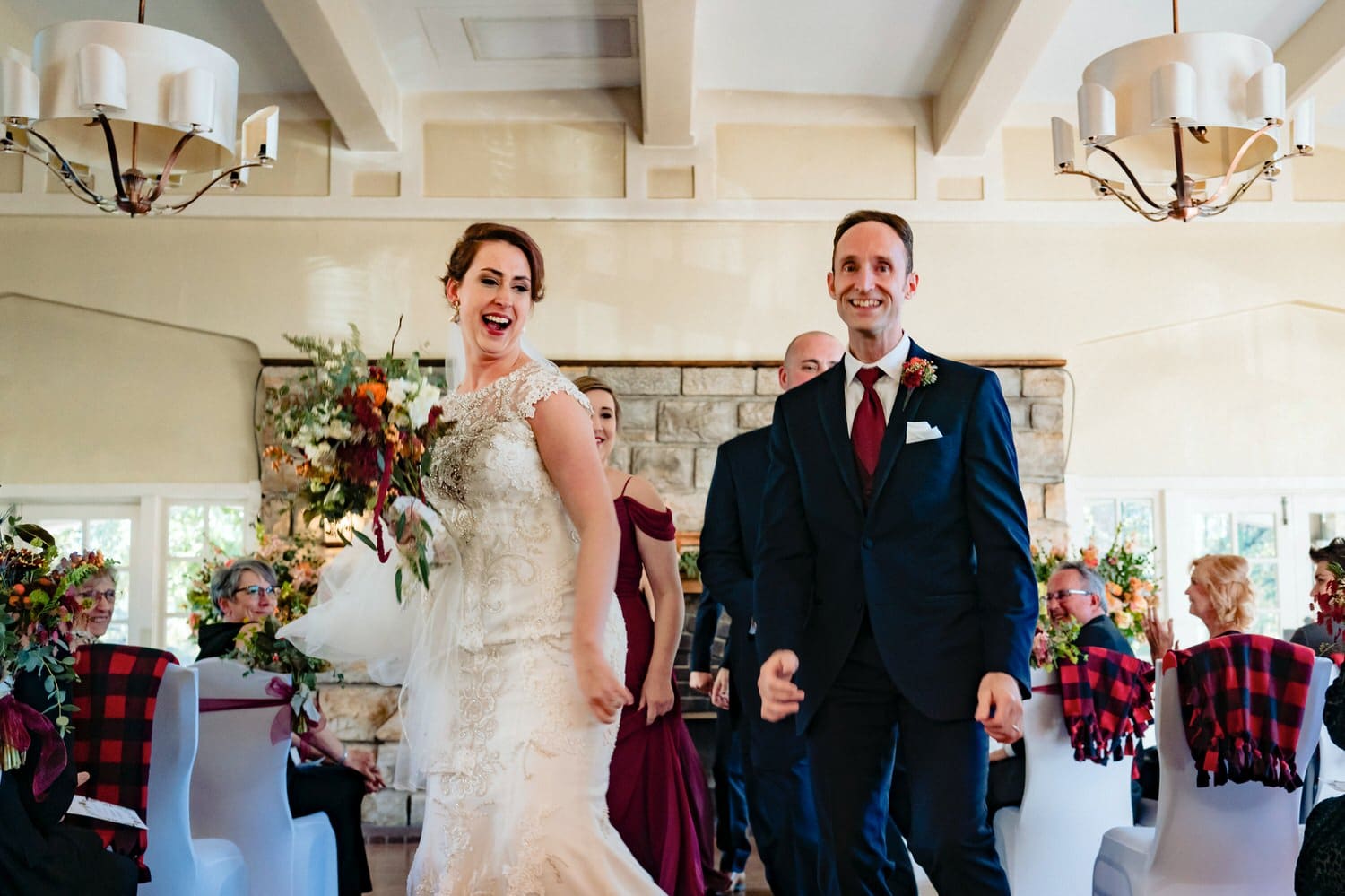 A colorful, candid picture of a bride and groom, bridesmaid and groomsman dancing down the aisle at the end of a wedding ceremony at The Elms. 