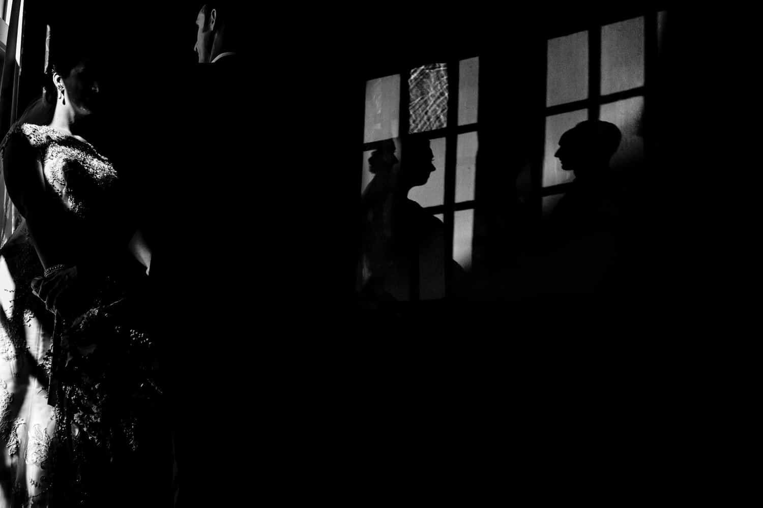 A dramatic black and white picture of the shadows of a bride and groom visible on a wall behind them at The Elms. 
