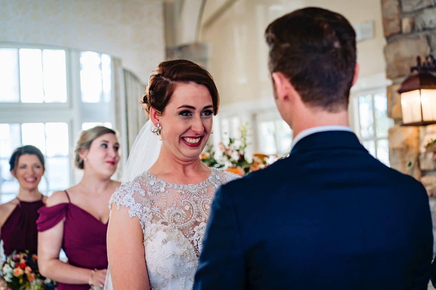 A colorful, candid picture of a bride smiling happily at her groom as she tries not to cry during their winter wedding ceremony at The Elms. 