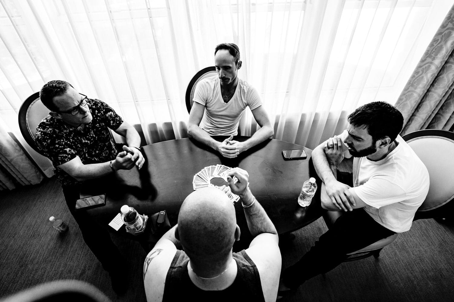 A candid black and white picture of four men seated around a table playing cards at The Elms. 