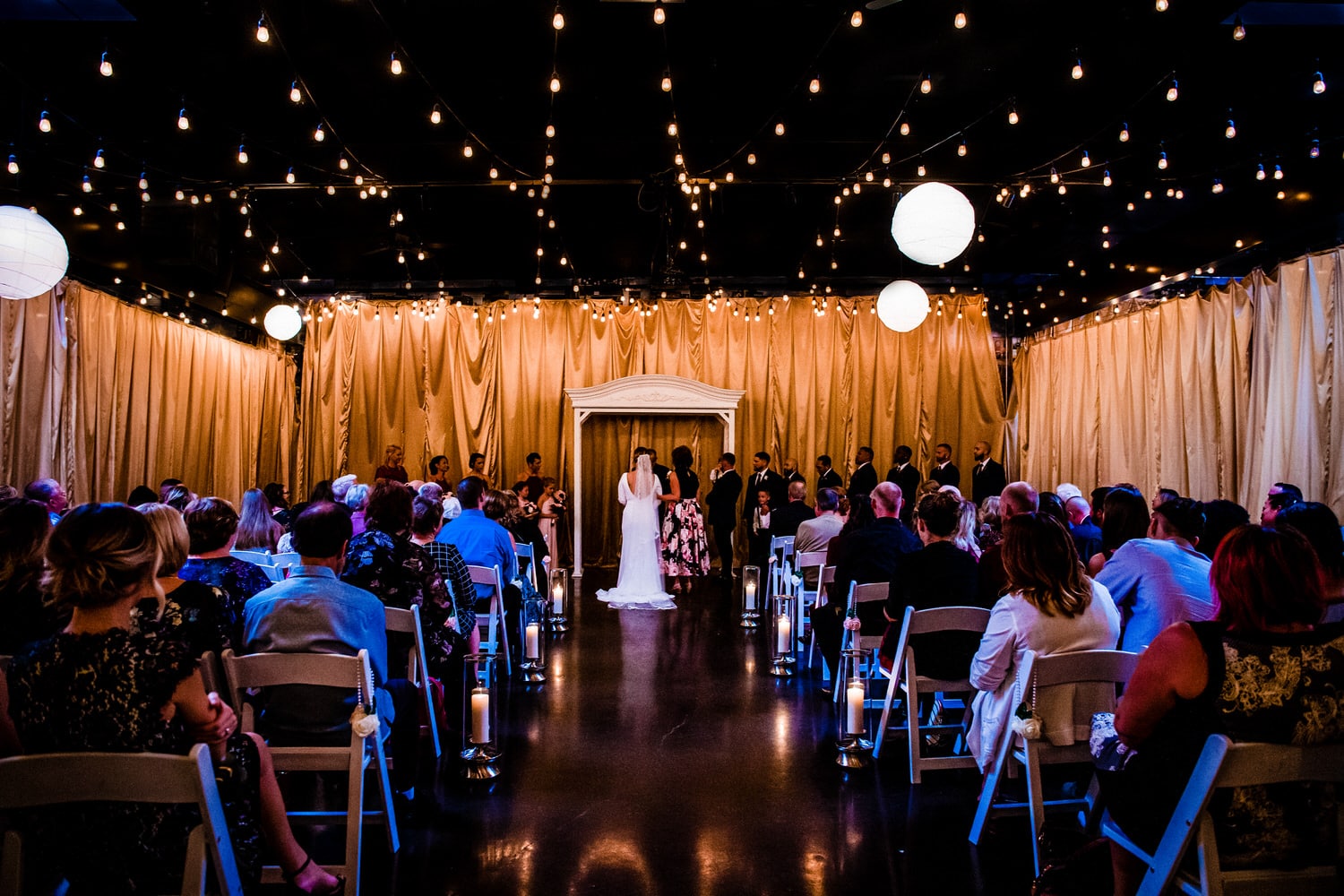 A bride standing at an altar with her mom and groom during an inside wedding ceremony in The Kansas City Room at 28 Event Space. 