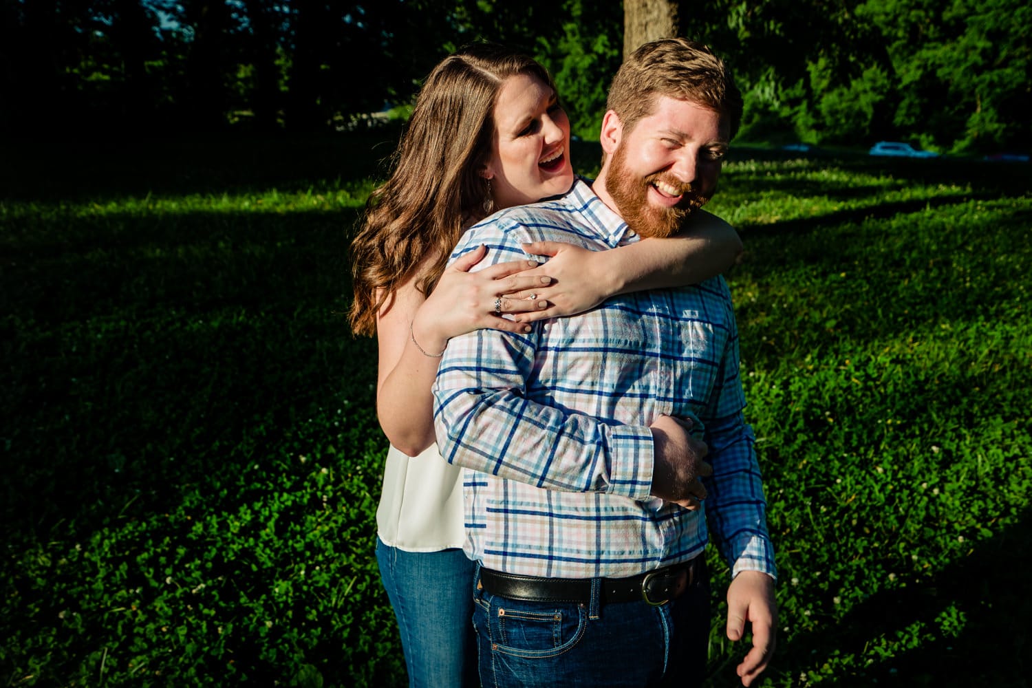 A candid picture of an engaged couple laughing and embracing during their summer engagement session. 