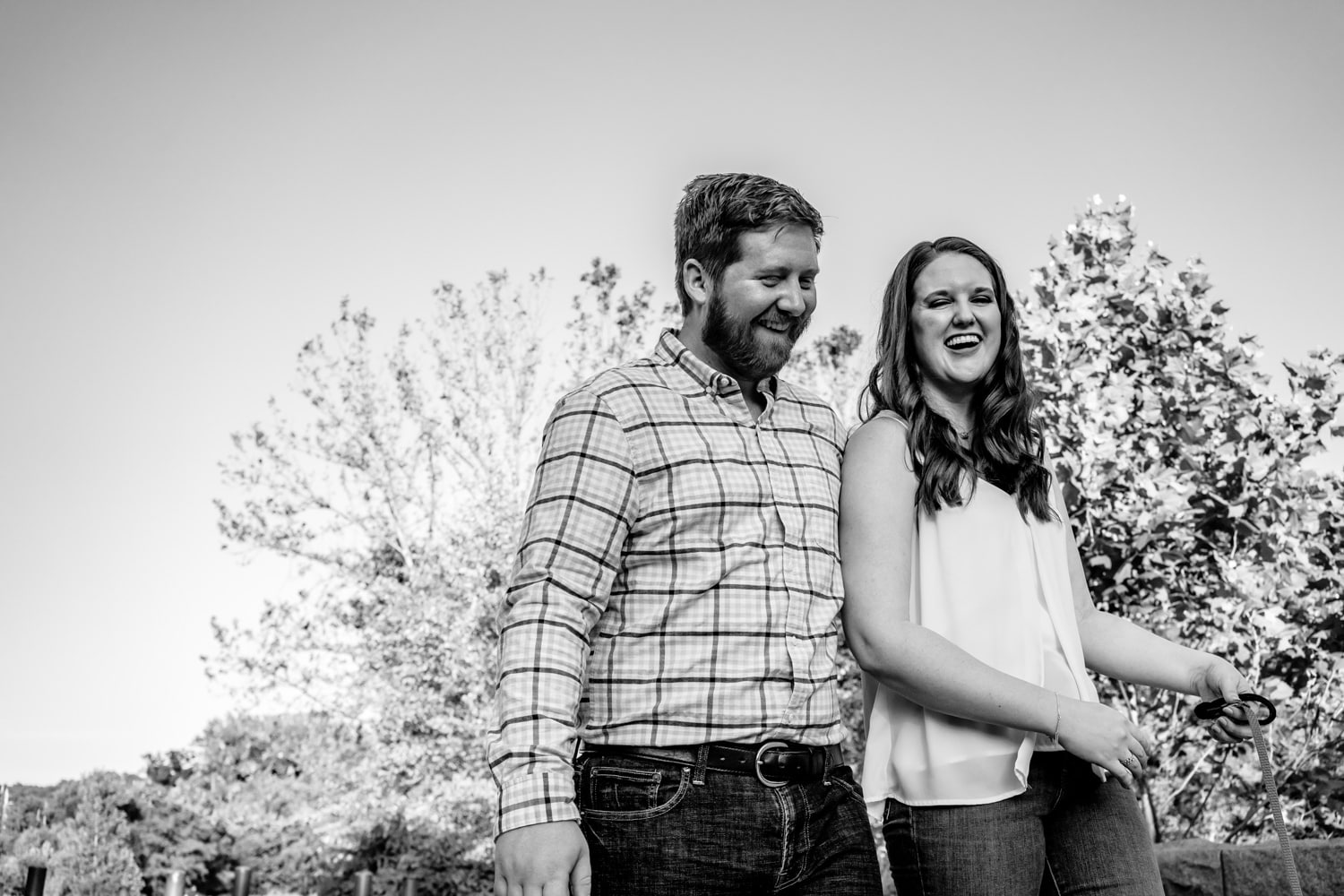A candid black and white picture of an engaged couple laughing together during their Kansas City engagement session. 