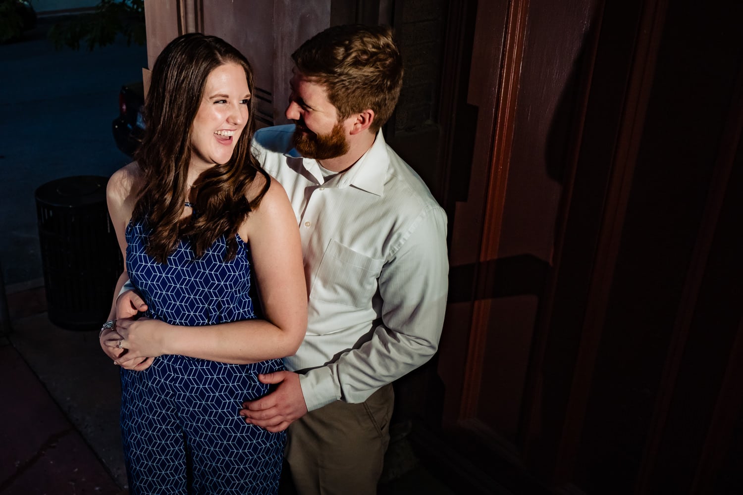 A candid picture of an engaged couple laughing and embracing during their summer engagement session in Kansas City. 