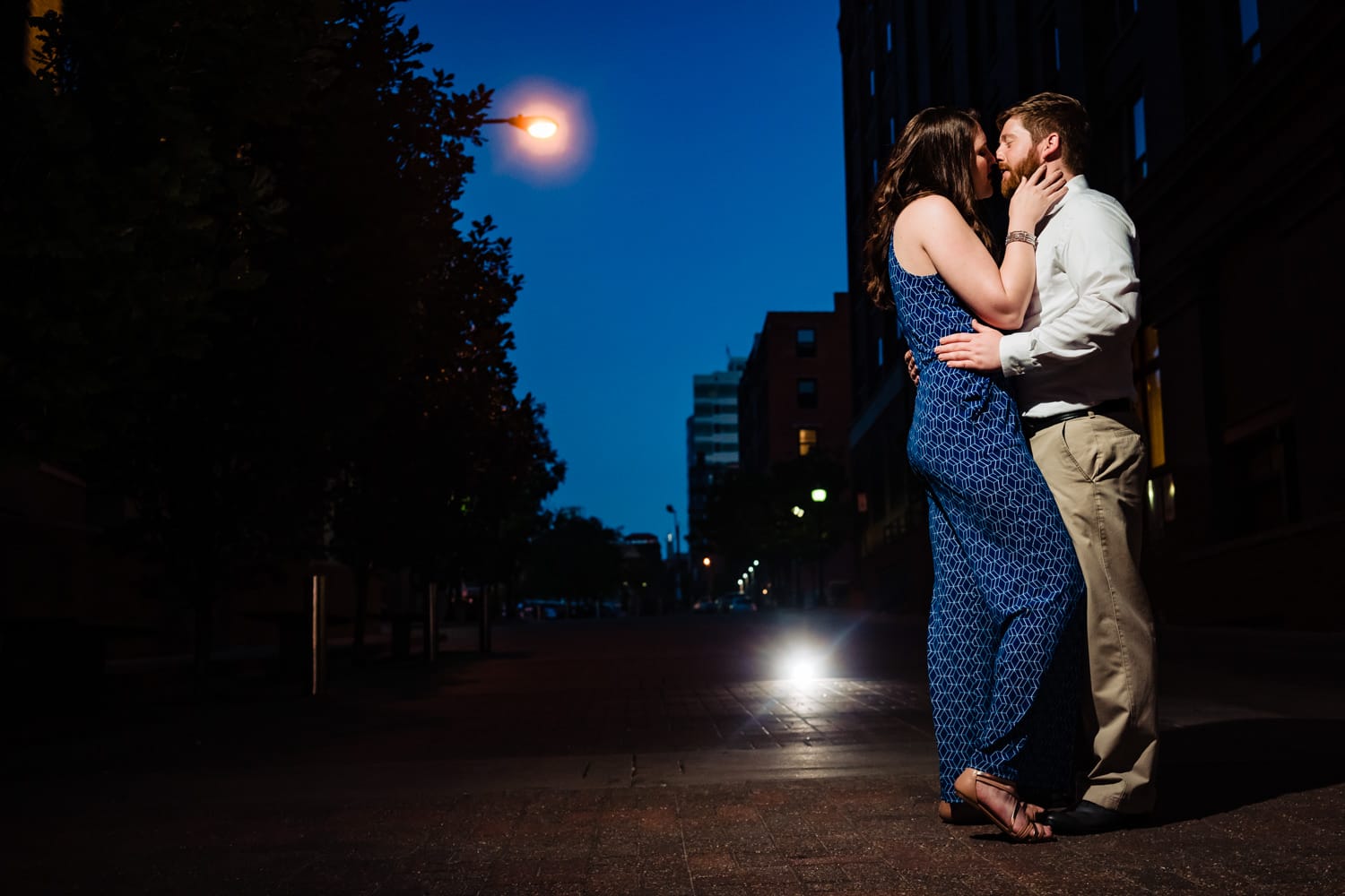 A colorful, candid picture of an engaged couple sharing a kiss during their downtown Kansas City engagement session. 