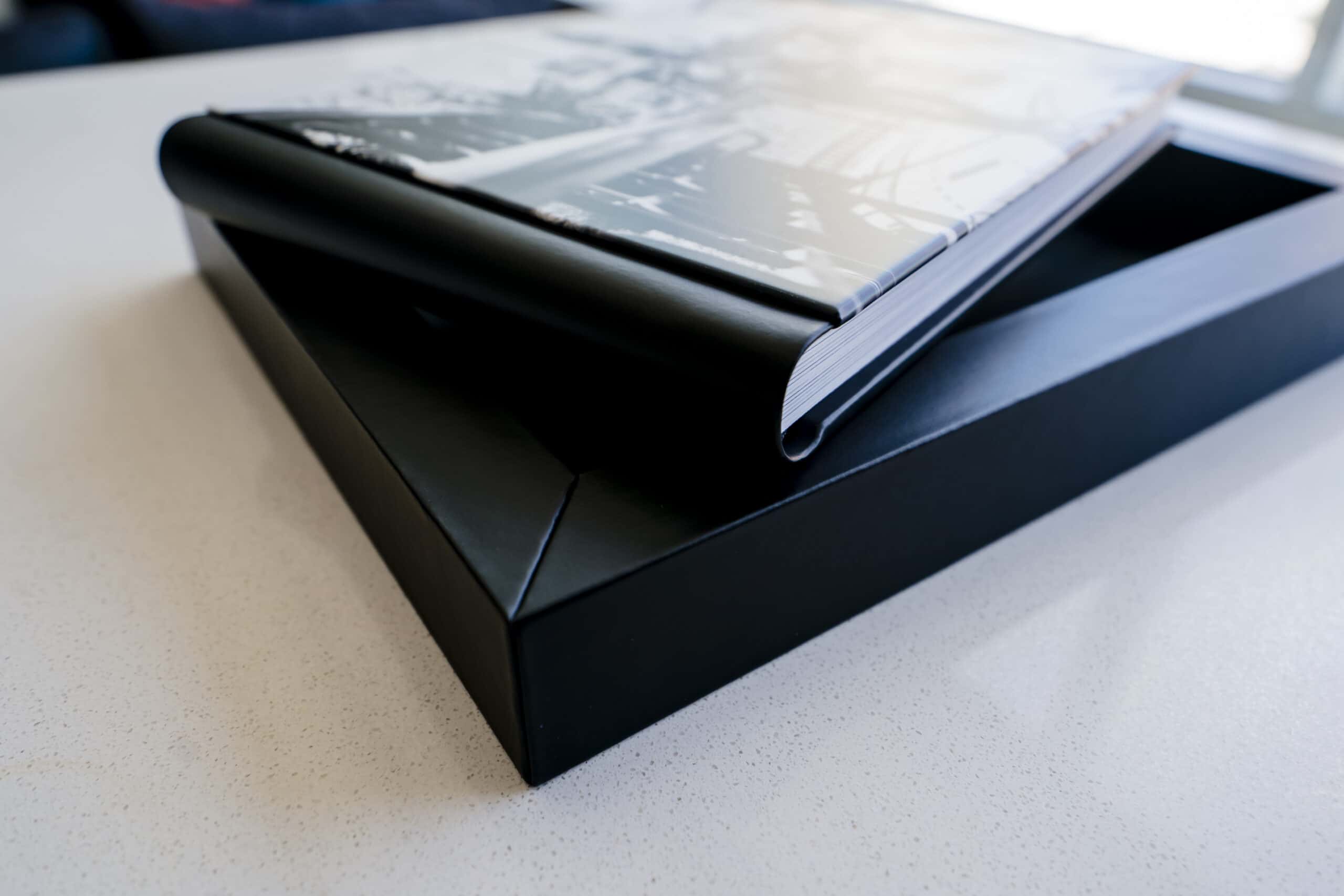 A black leather covered wedding album with a black and white picture of a bride and groom at Kansas City's Country Club Plaza on the cover. 
