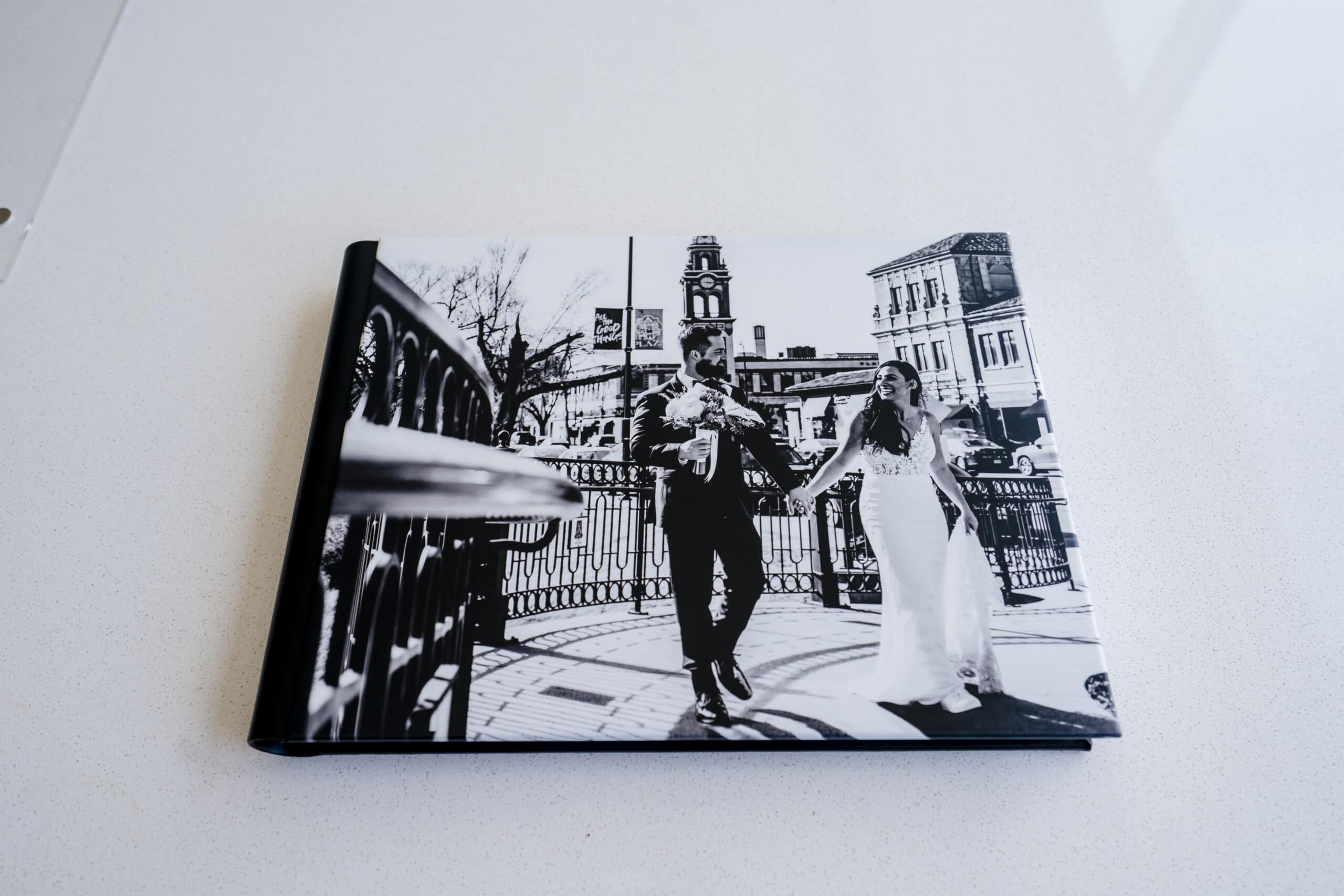 A black leather covered wedding album with a black and white picture of a bride and groom at Kansas City's Country Club Plaza on the cover. 
