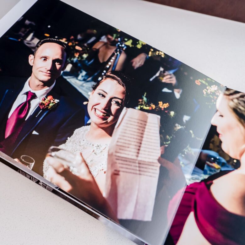 A picture of a couple laughing during a toast printed in a wedding album.