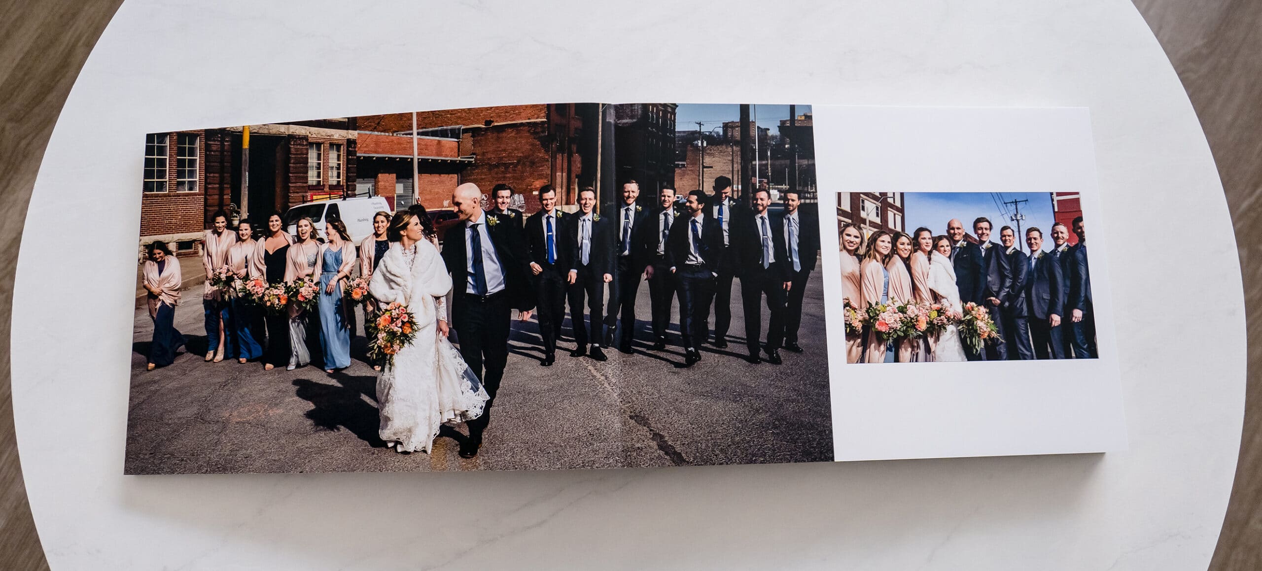A picture of a wedding album laying open, showing a bride and groom with their wedding party.