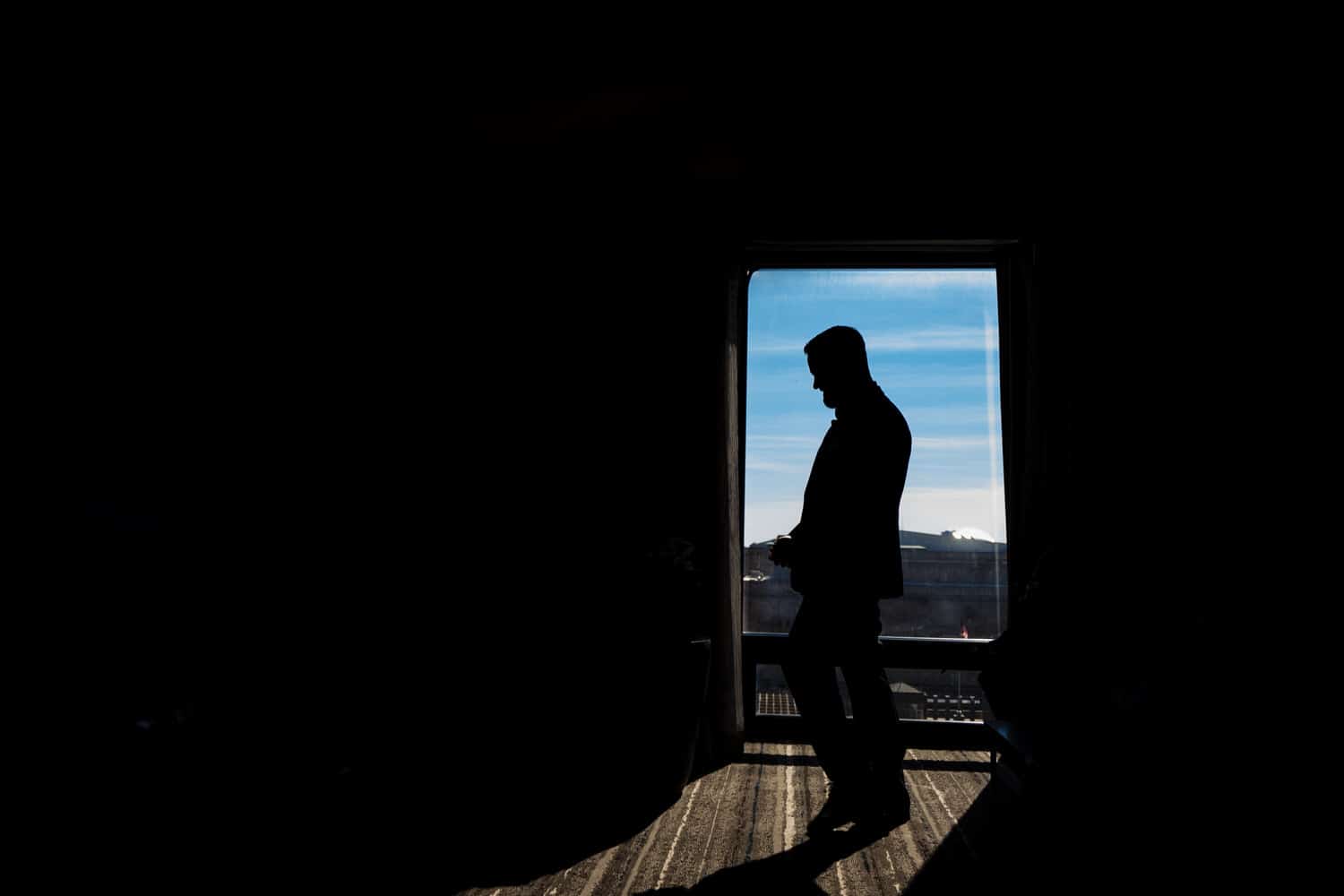 A dramatic silhouette of a groom on the day of his wedding day. 