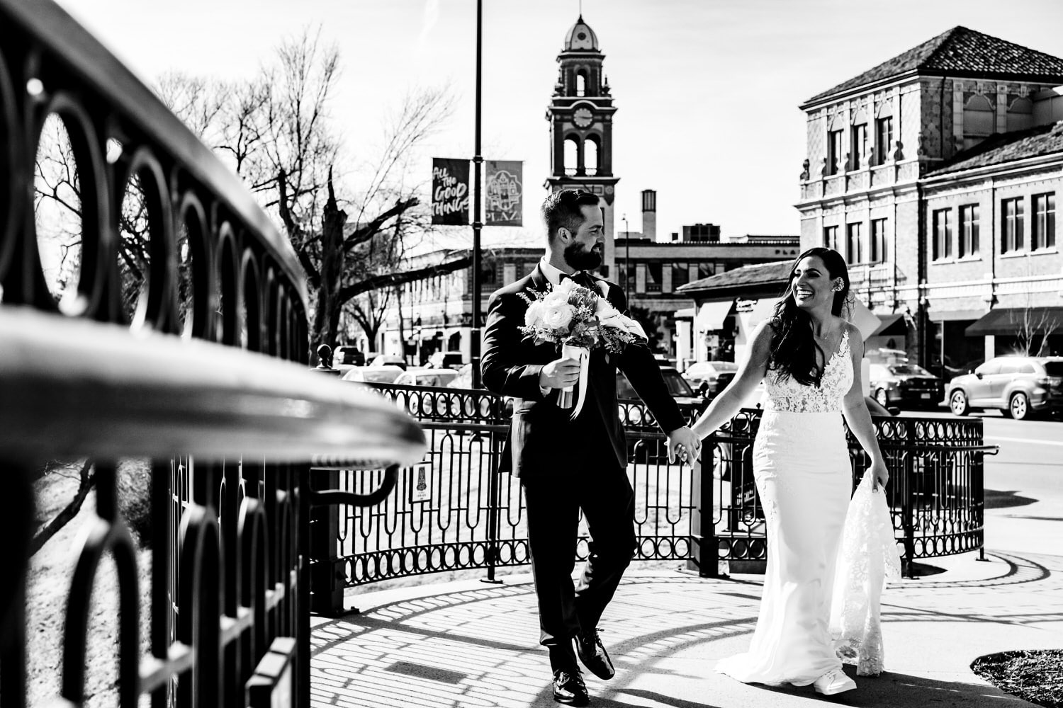 A candid black and white picture of a bride and groom walking hand in hand down the sidewalk of the Country Club Plaza in Kansas City on a winter wedding day. 