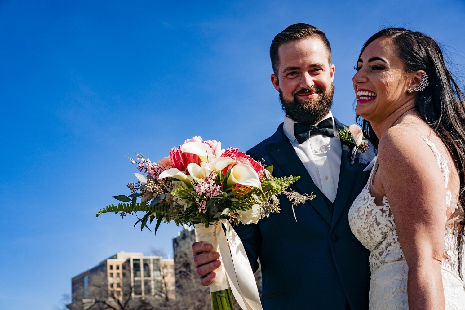 A close-up, candid picture of a bride and groom laughing together on a sunny wedding day in Kansas City. 