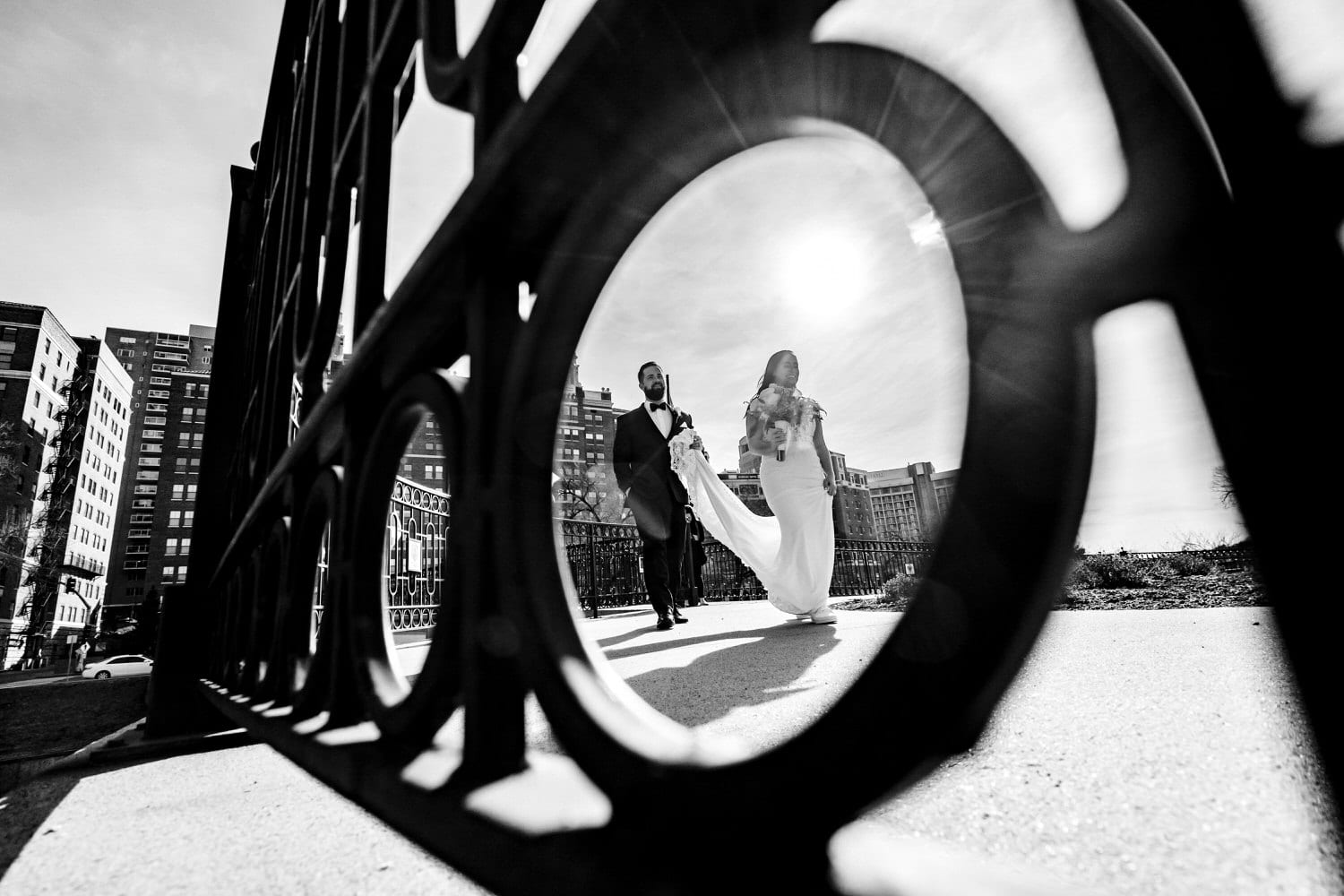 A candid black and white picture of a bride and groom walking hand in hand down the sidewalk of the Country Club Plaza in Kansas City on a winter wedding day. 