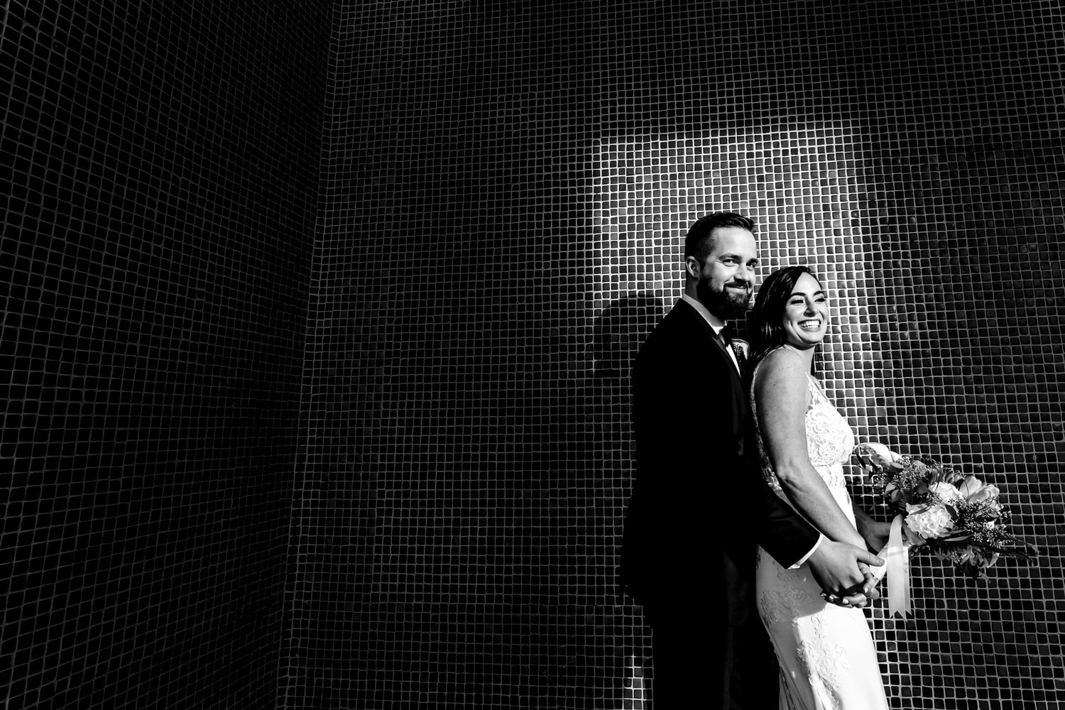 A dramatic black and white portrait of a bride and groom standing in a rectangle of sunshine at Liberty Memorial on their winter wedding day in Kansas City. 