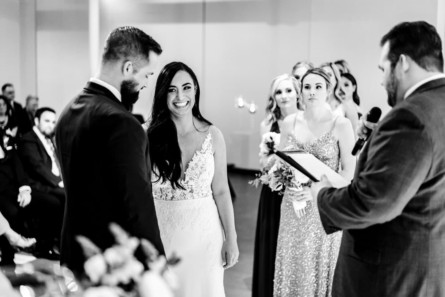A candid black and white picture of a bride smiling at her groom during a winter wedding ceremony at Pennway Place in Kansas City. 