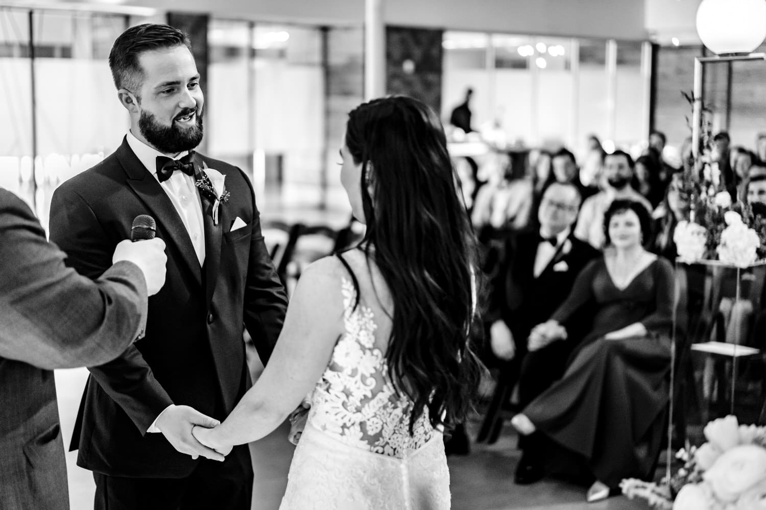 A candid black and white picture of a groom smiling at his bride during a winter wedding ceremony at Pennway Place in Kansas City. 