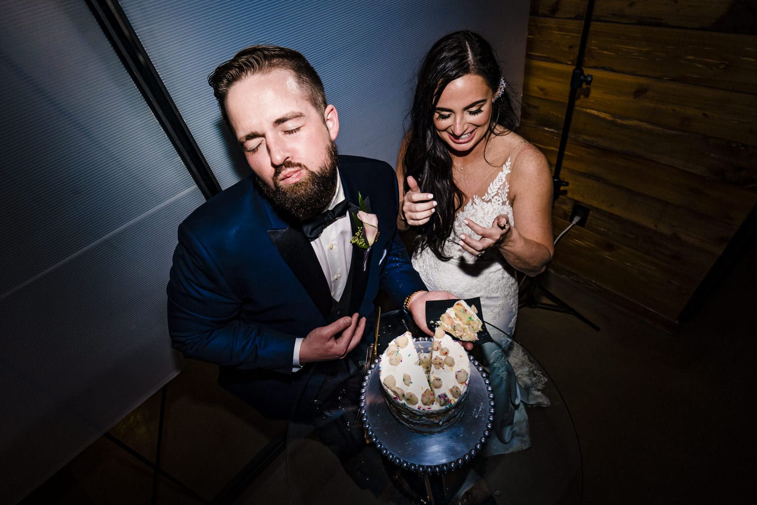 A candid, close-up picture of a bride and groom laughing as they cut their Milk Bar wedding cake during a wedding reception at Pennway Place in Kansas City. 