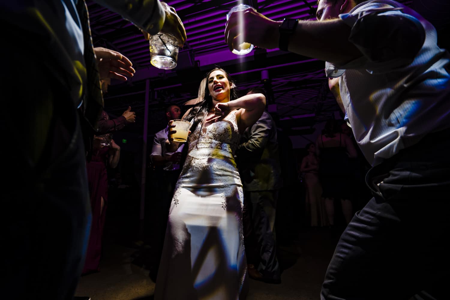 A canid, colorful picture of a bride dancing with wedding guests during a wedding reception at Pennway place in Kansas City. 