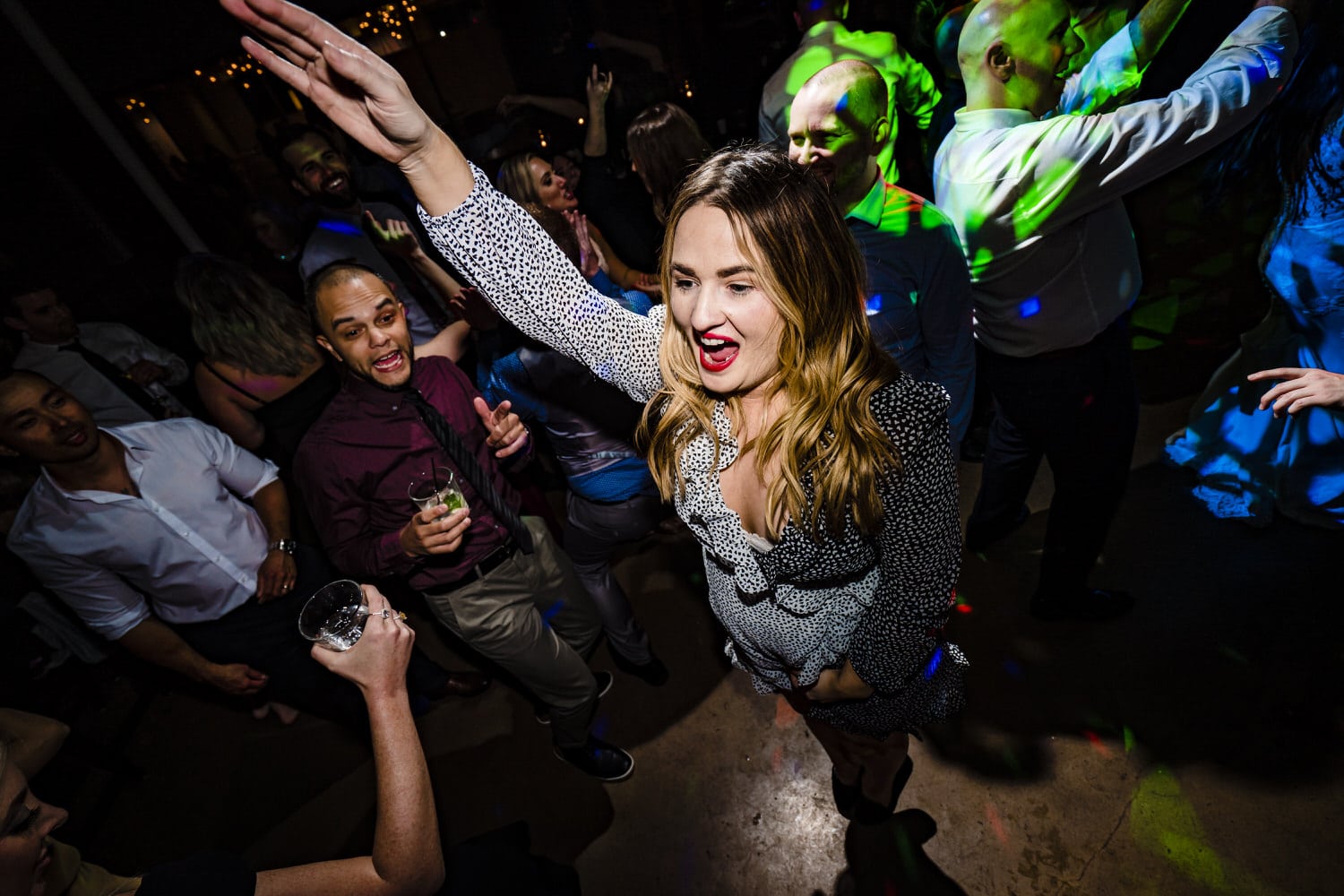 A picture of wedding guests excitedly and enthusiastically dancing and singing along to the music during a wedding reception at Pennway Place in Kansas City. 