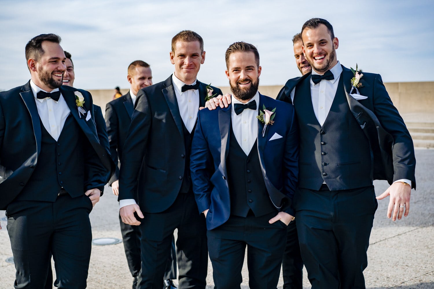 A colorful, candid picture of a groom and his groomsmen laughing uncontrollably on a sunny, winter wedding day in Kansas City. 