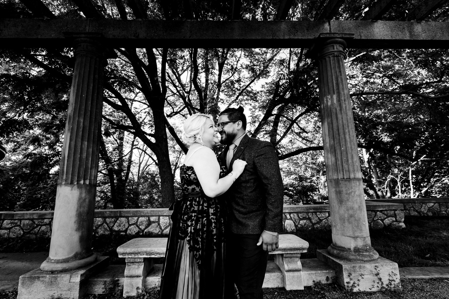 A candid black and white picture of an engaged couple laughing as they share an embrace during their romantic engagement session in Kansas City. 